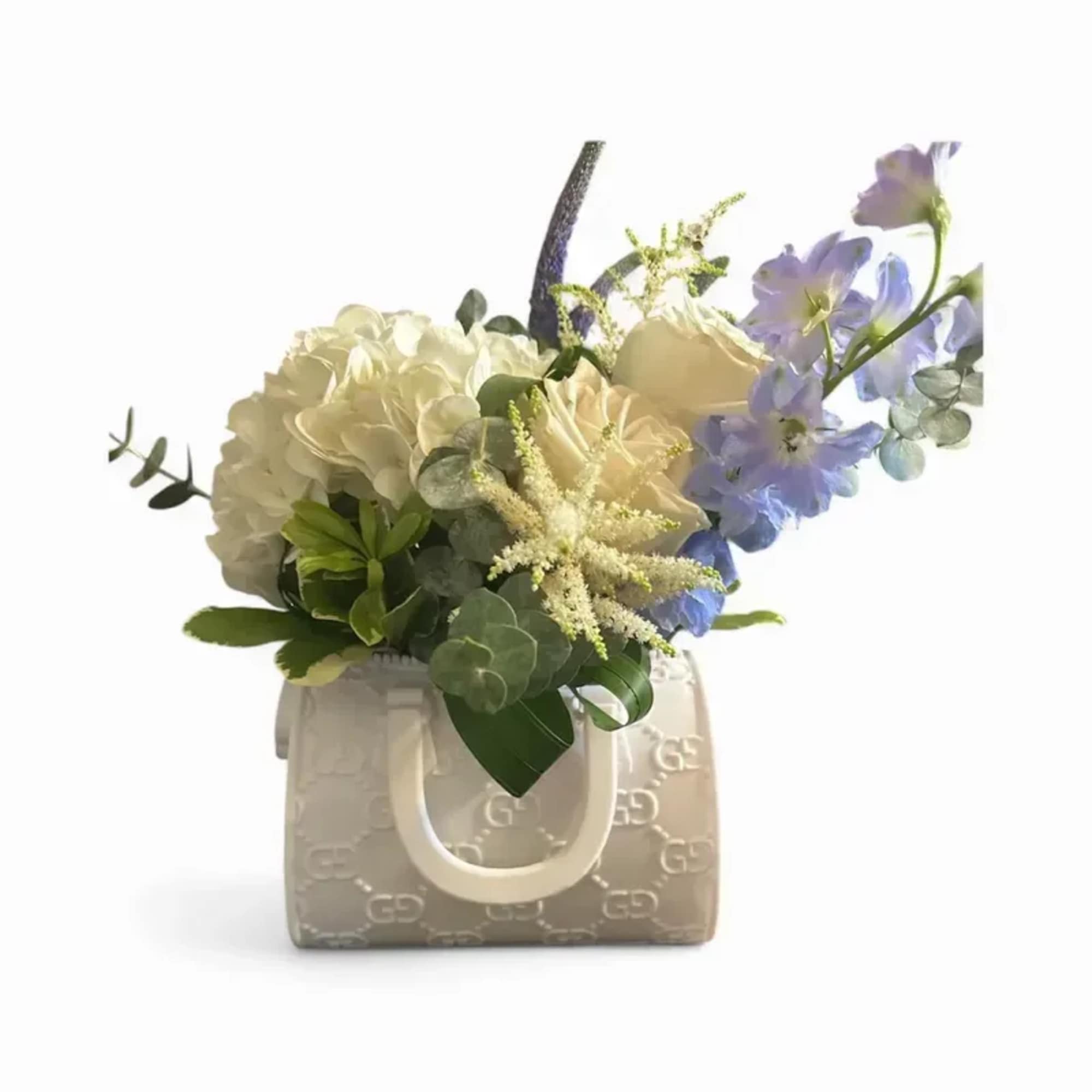 Soft white hydrangeas and pale cream roses mingle with airy lavender-blue delphinium