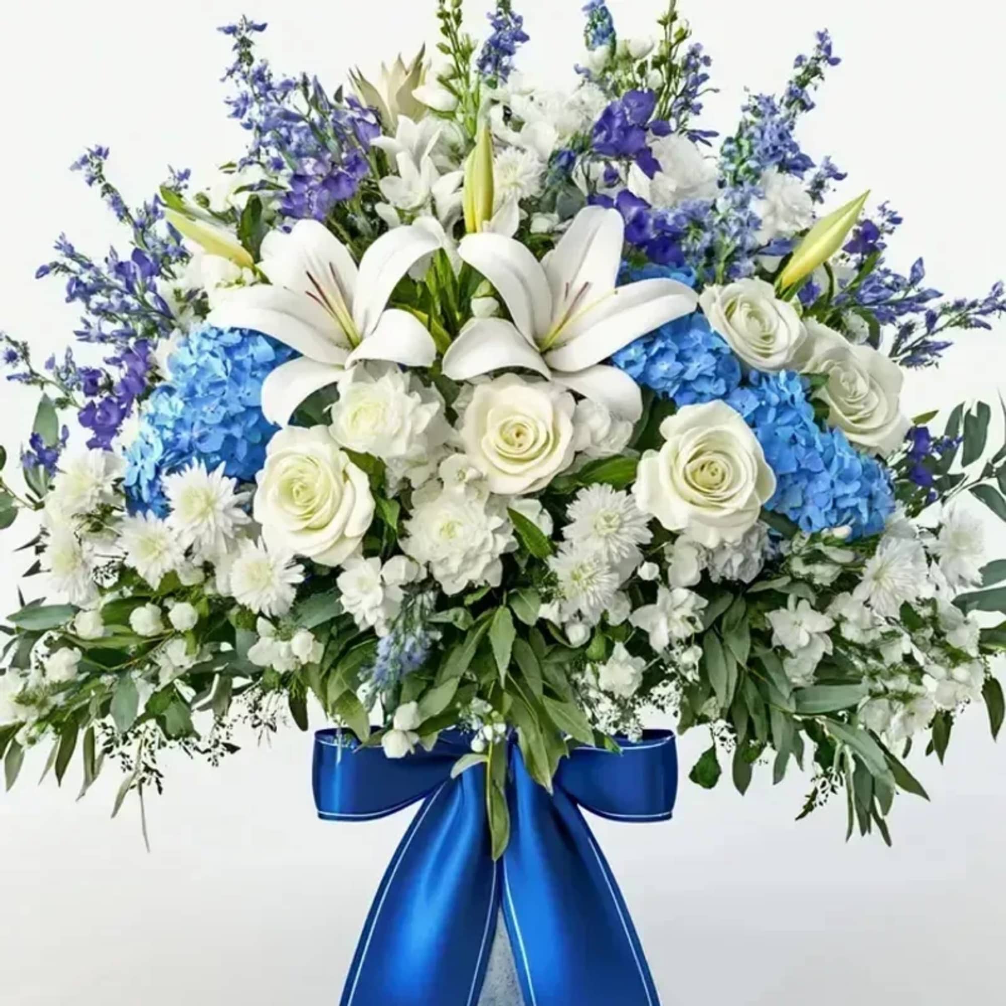 A dignified cascade of white lilies and roses set against vivid blue