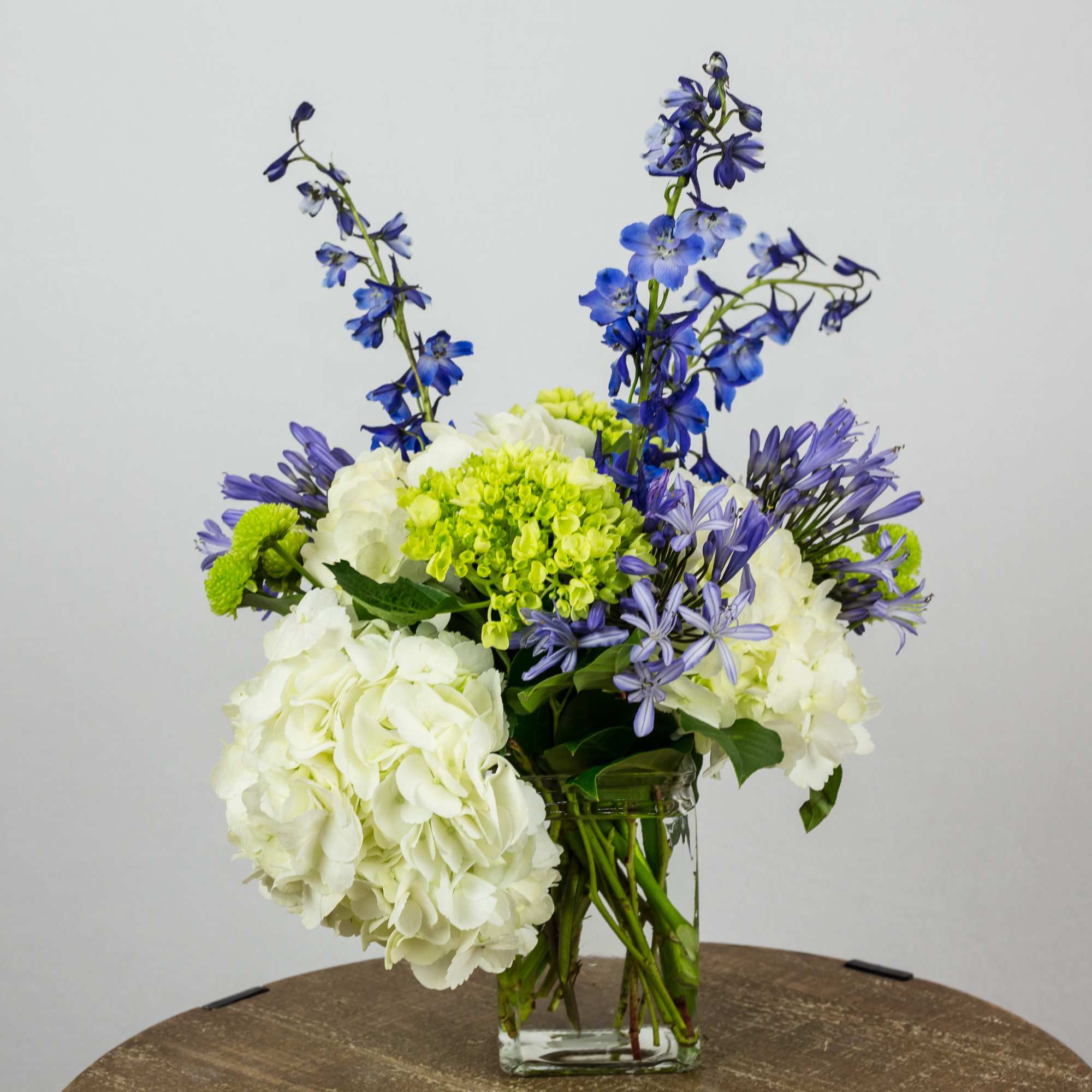 Blue and white mixed flower arrangement in a clear glass vase