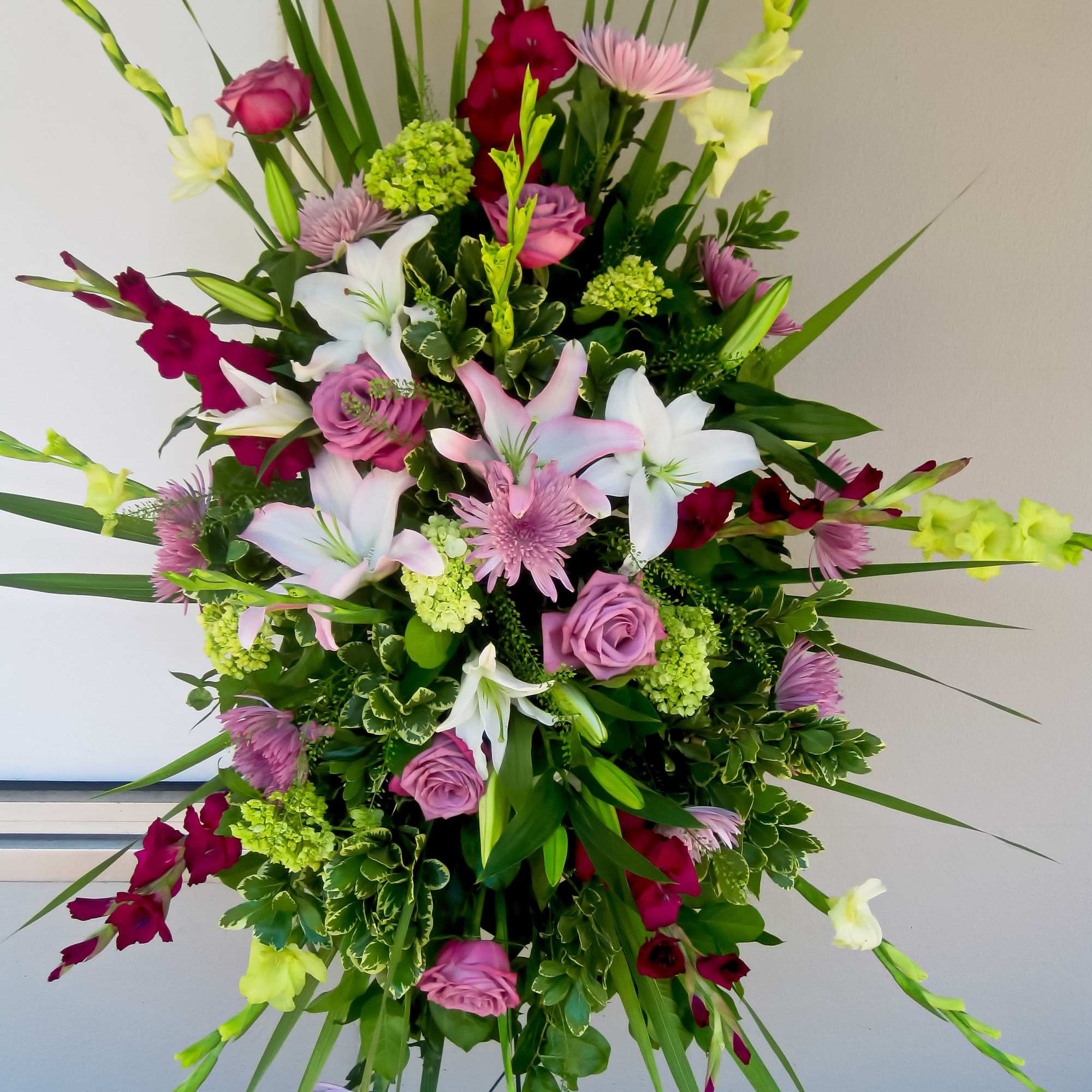 Tall floral arrangement with pink, white, and burgundy blooms