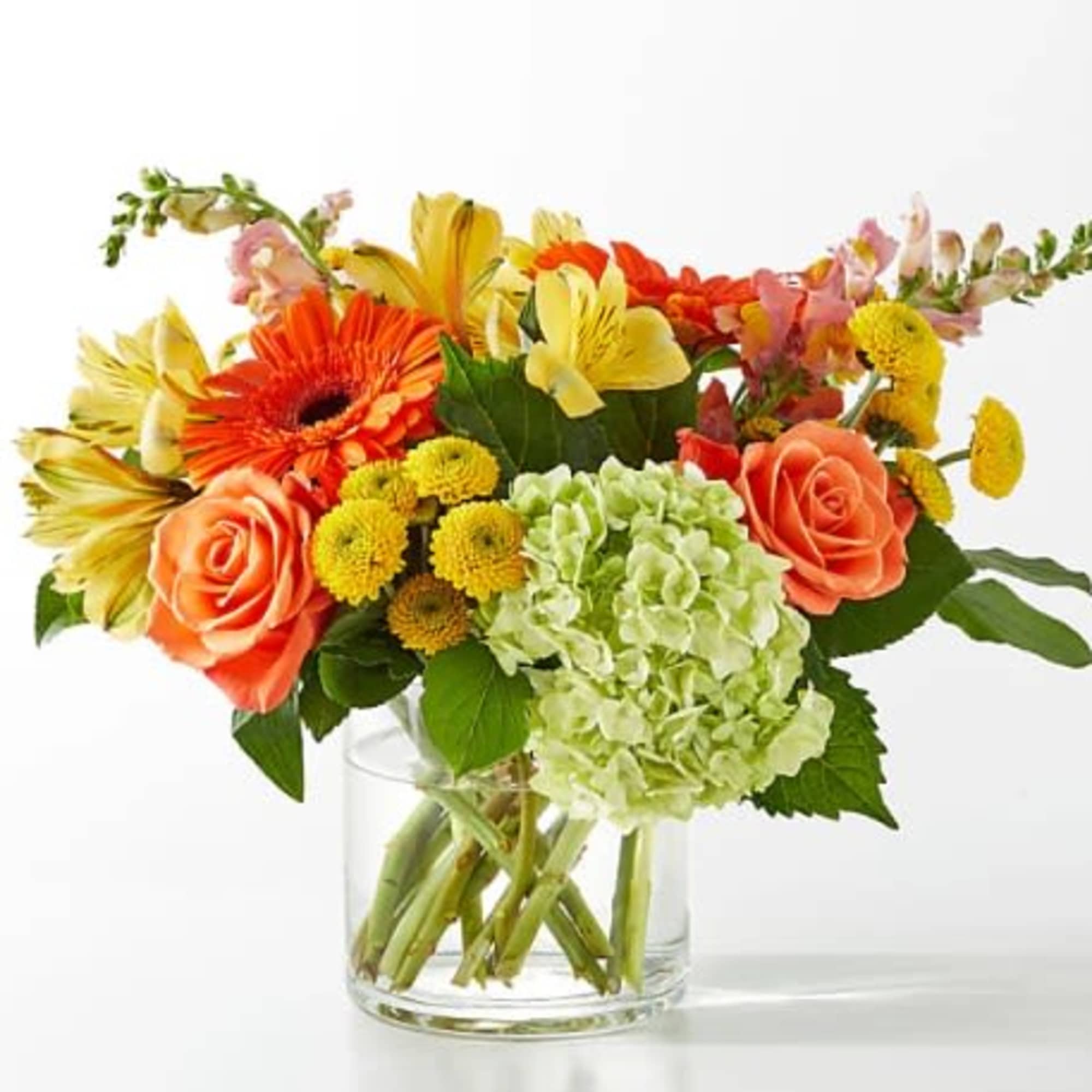 Mixed bouquet of orange, yellow, and pink flowers in a clear glass vase