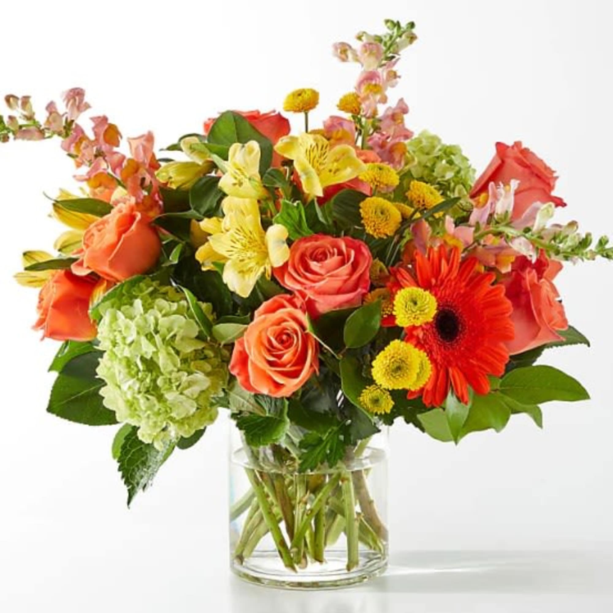 Mixed bouquet of roses, lilies, gerbera daisies, and hydrangea in a glass vase