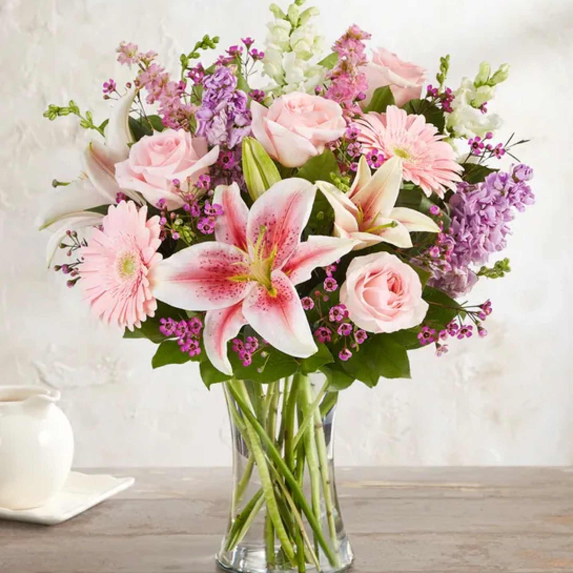 Pink roses, lilies, and daisies in a clear glass vase