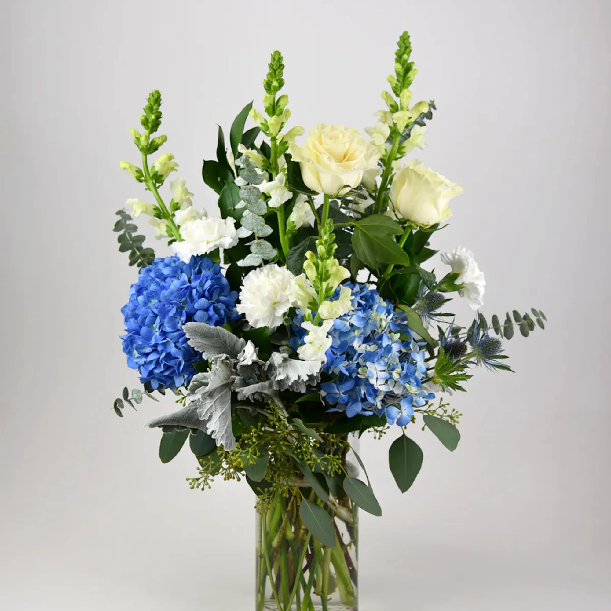 This heavenly arrangement of white flowers with blue accent blooms sends a