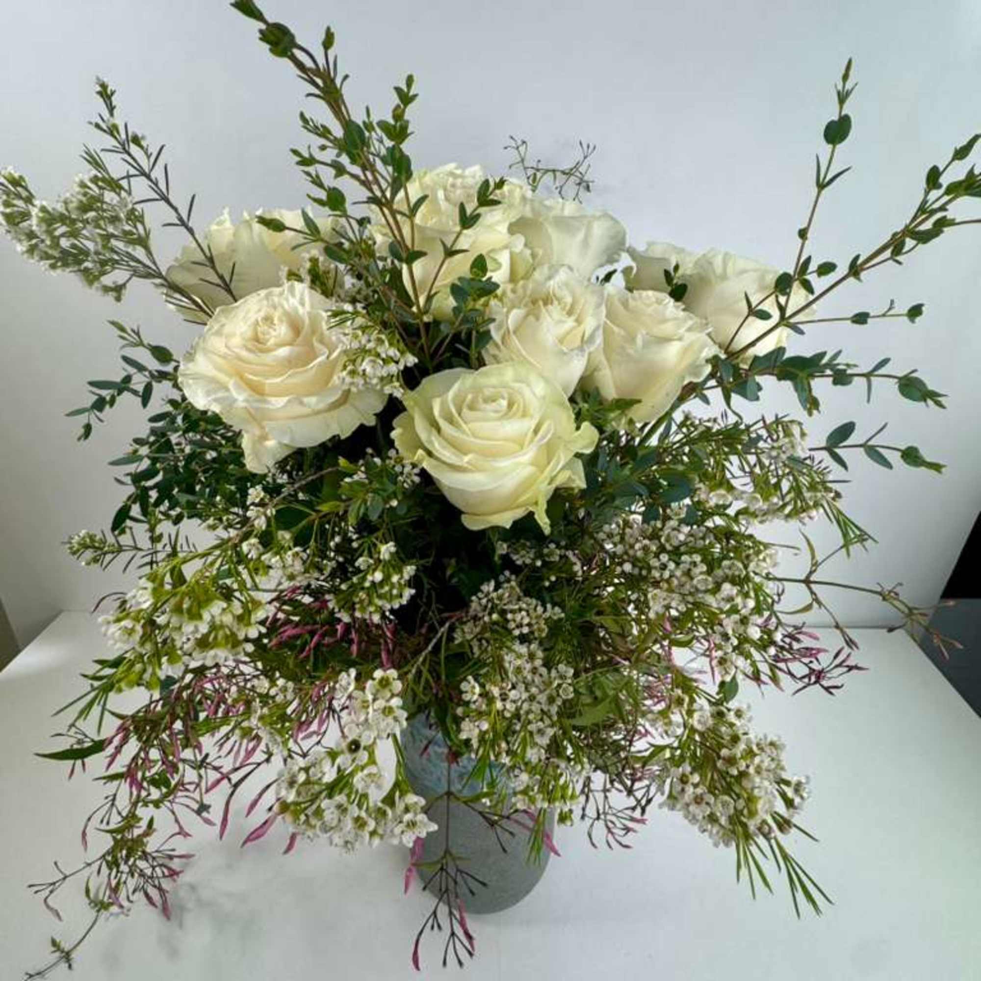 White rose arrangement in a gray vase with airy greenery