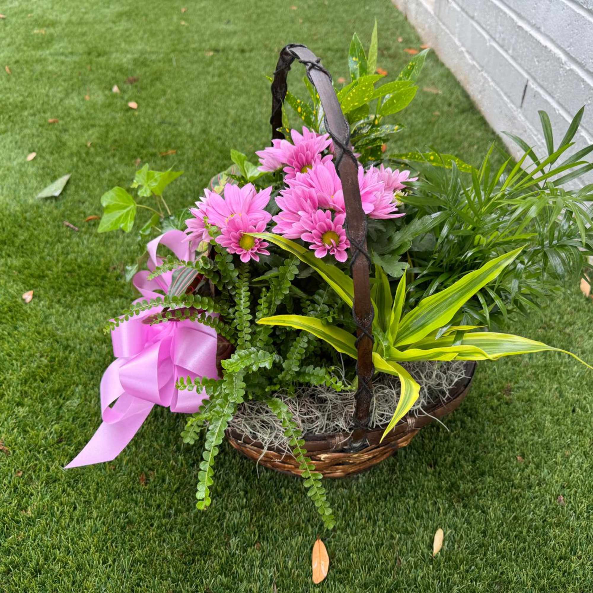Pink daisies in a wicker basket with a pink ribbon