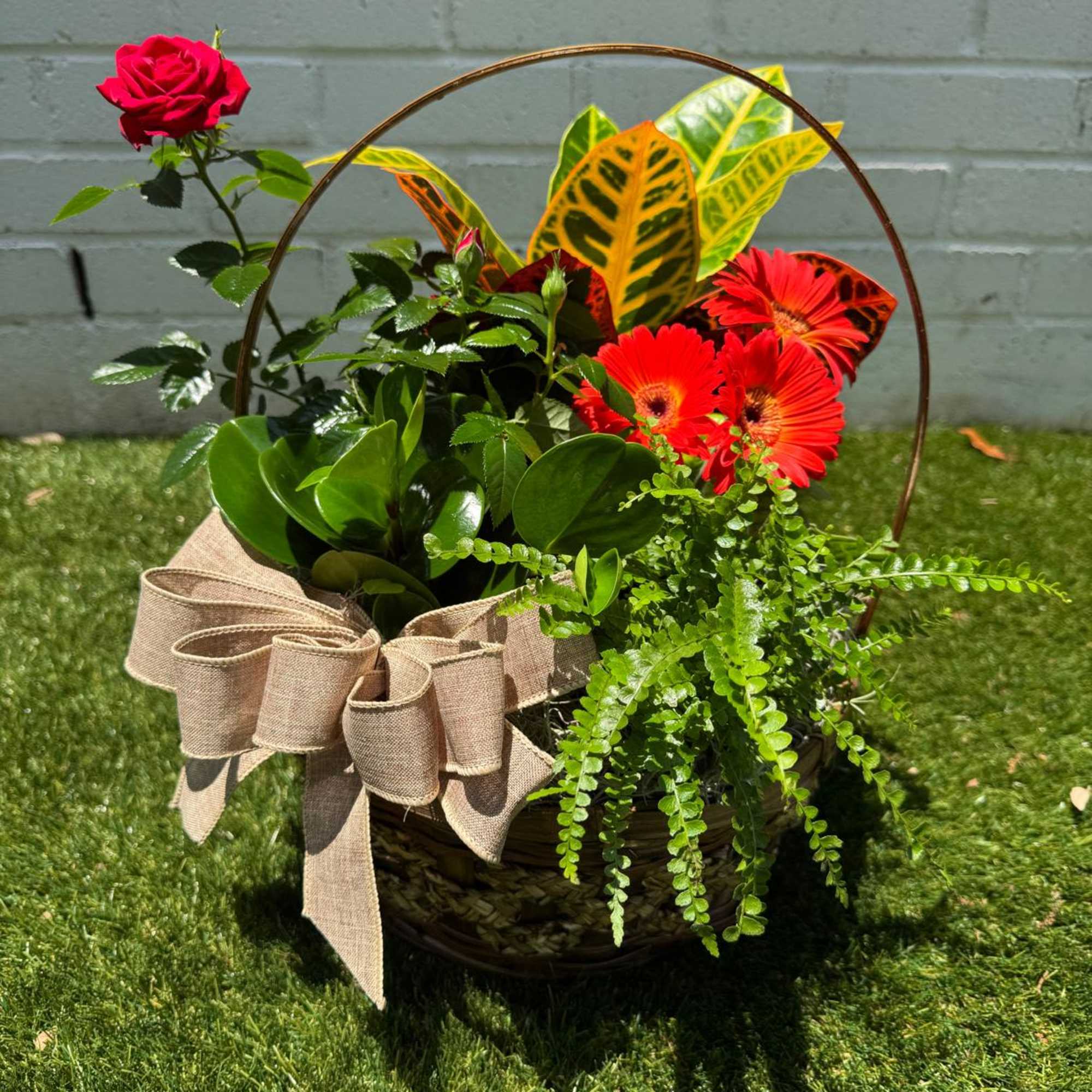 Basket arrangement with a red rose and orange gerbera daisies