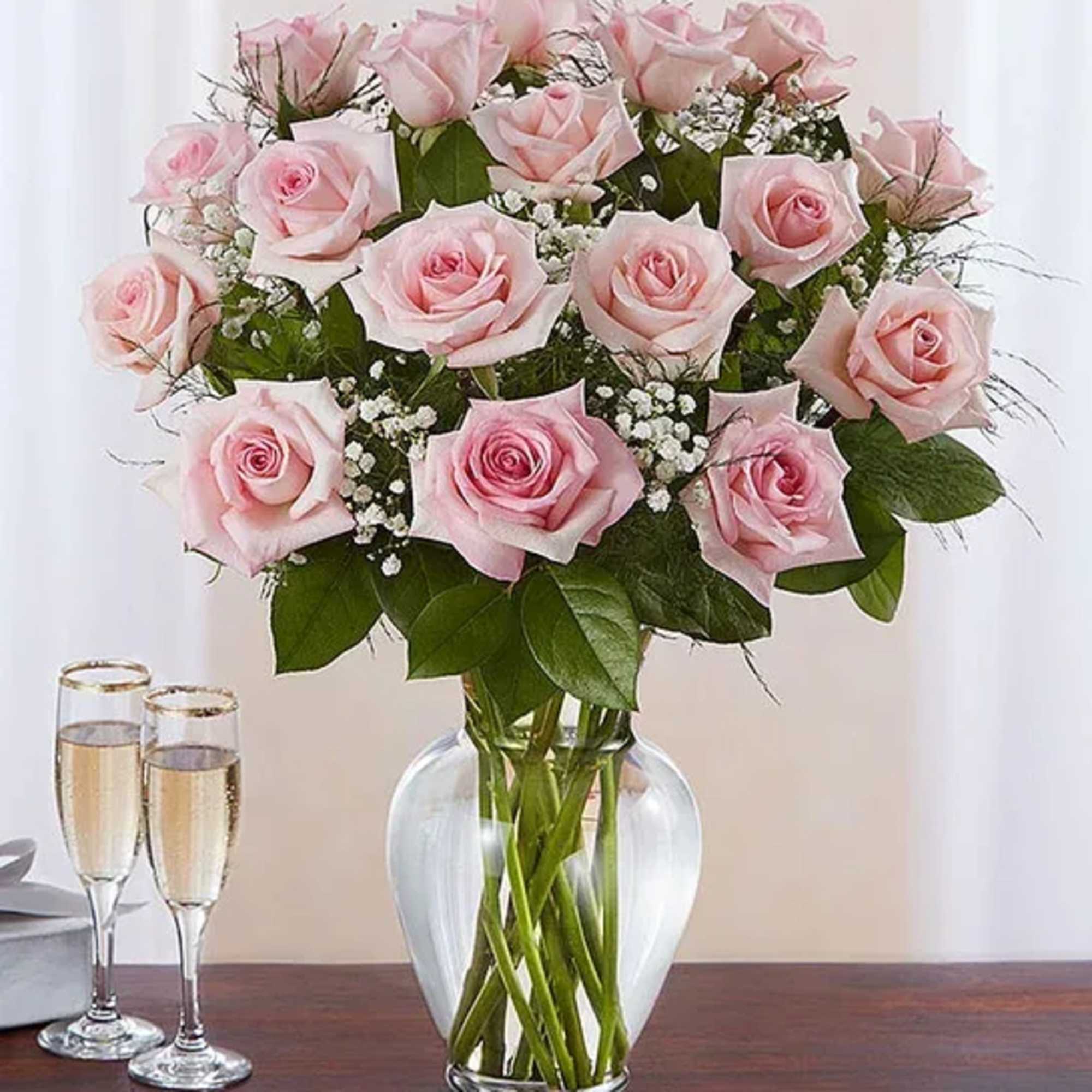 Pink roses arranged in a clear glass vase with baby’s breath