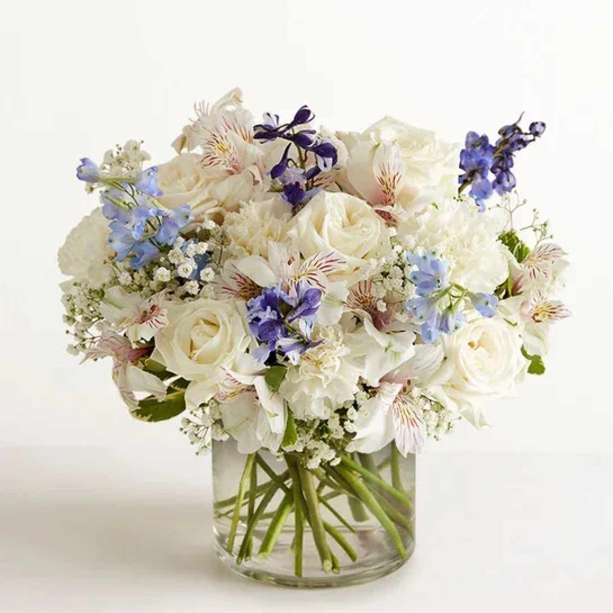 White and blue mixed bouquet in a clear glass vase