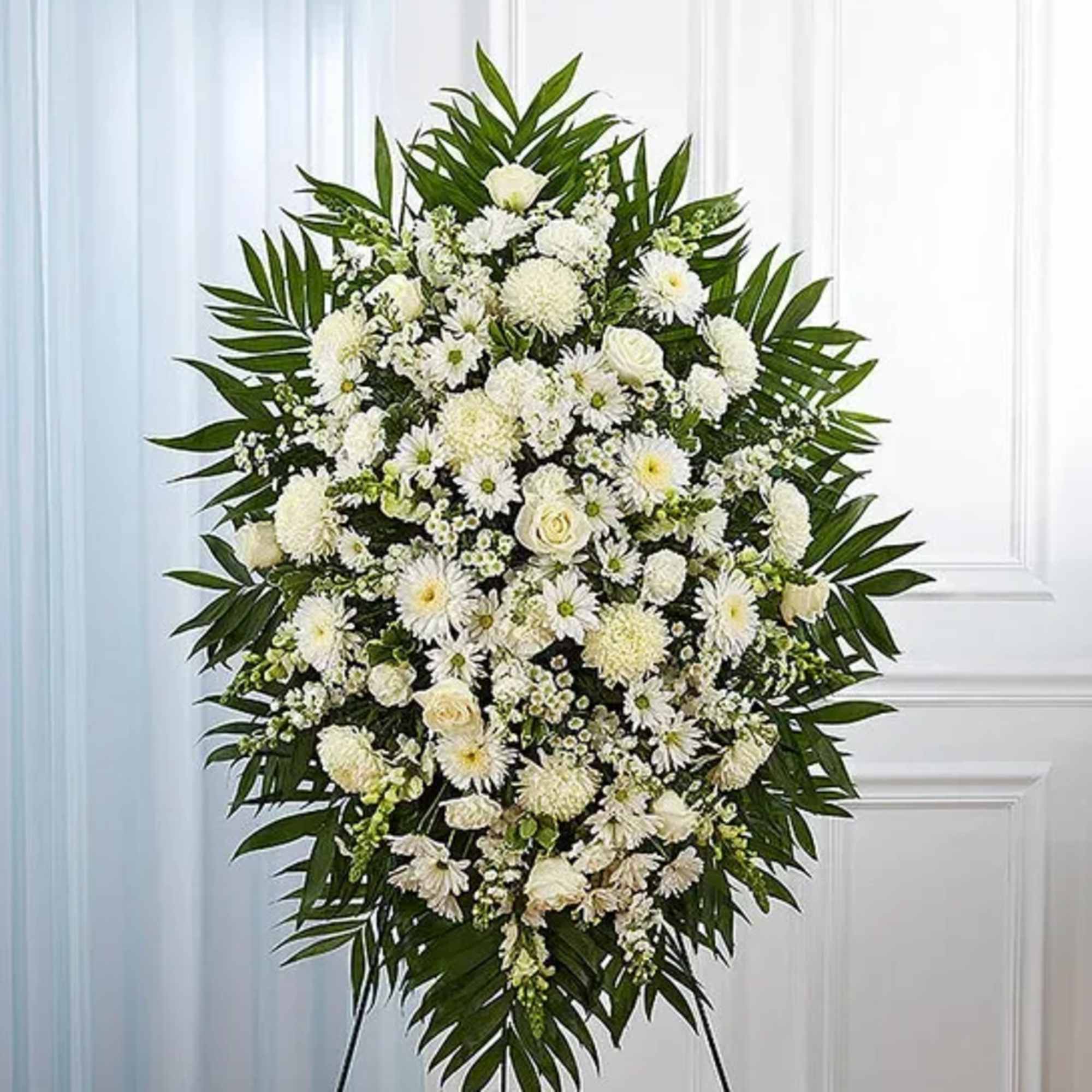 White funeral spray with daisies and roses on a stand