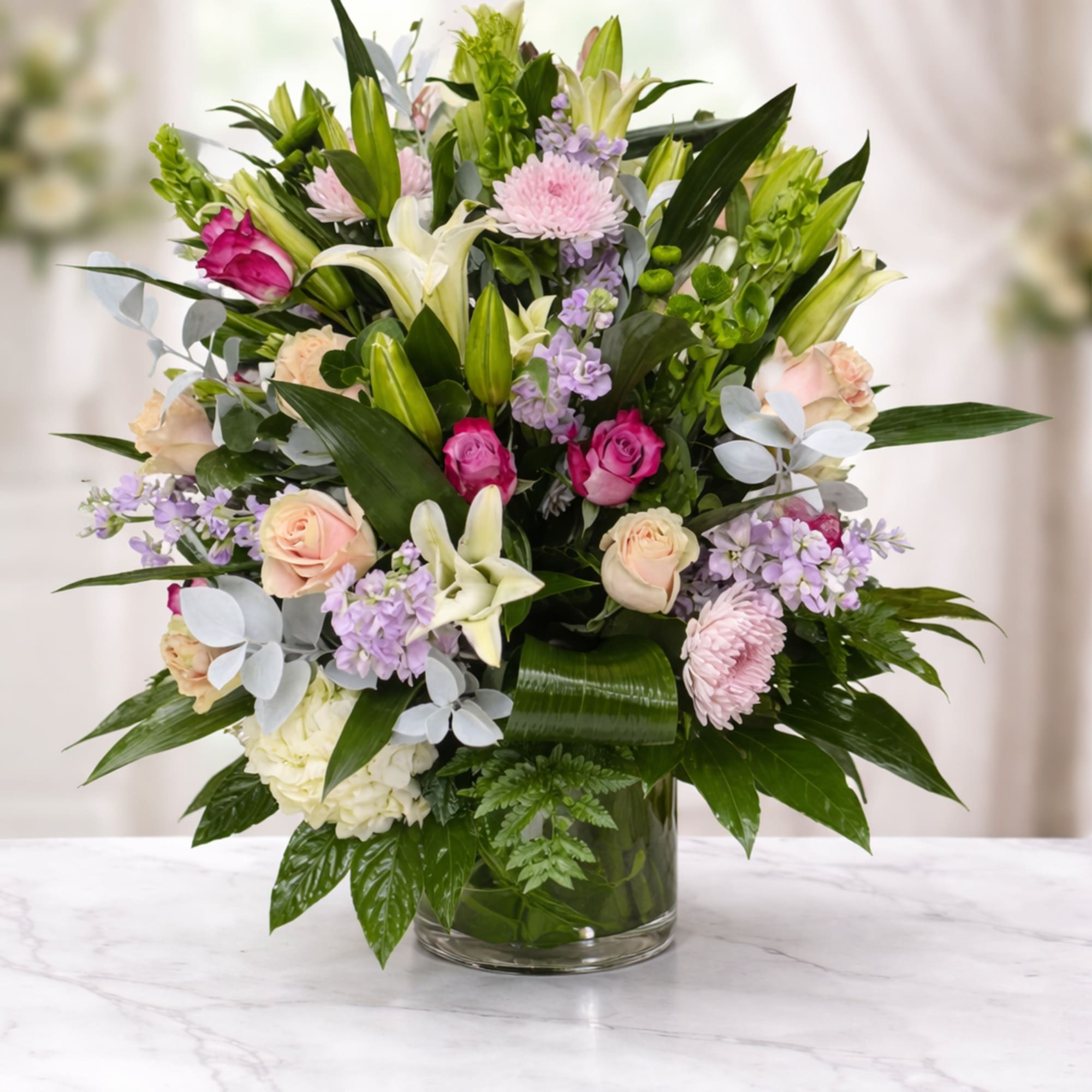 Mixed bouquet of pink, white, and lavender flowers in a glass vase