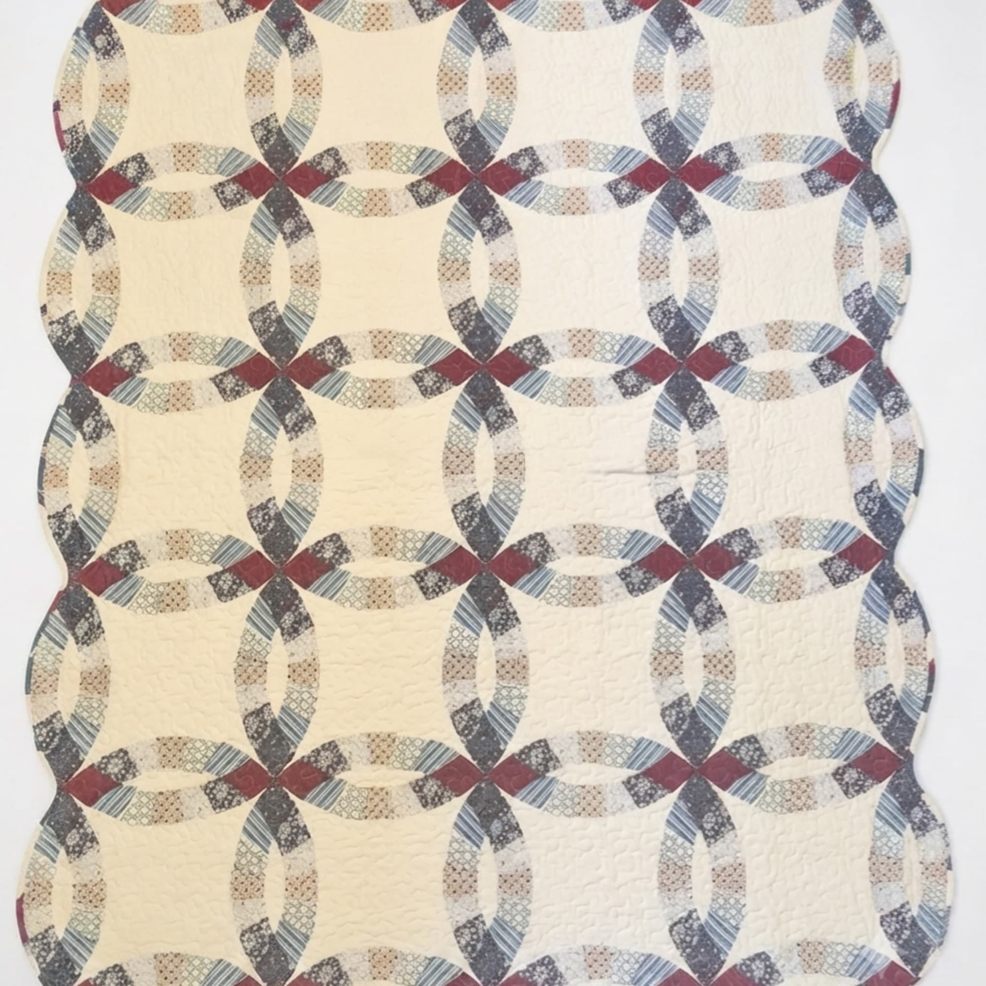 Cream quilt with a repeating oval chain pattern in muted red, blue, and gray