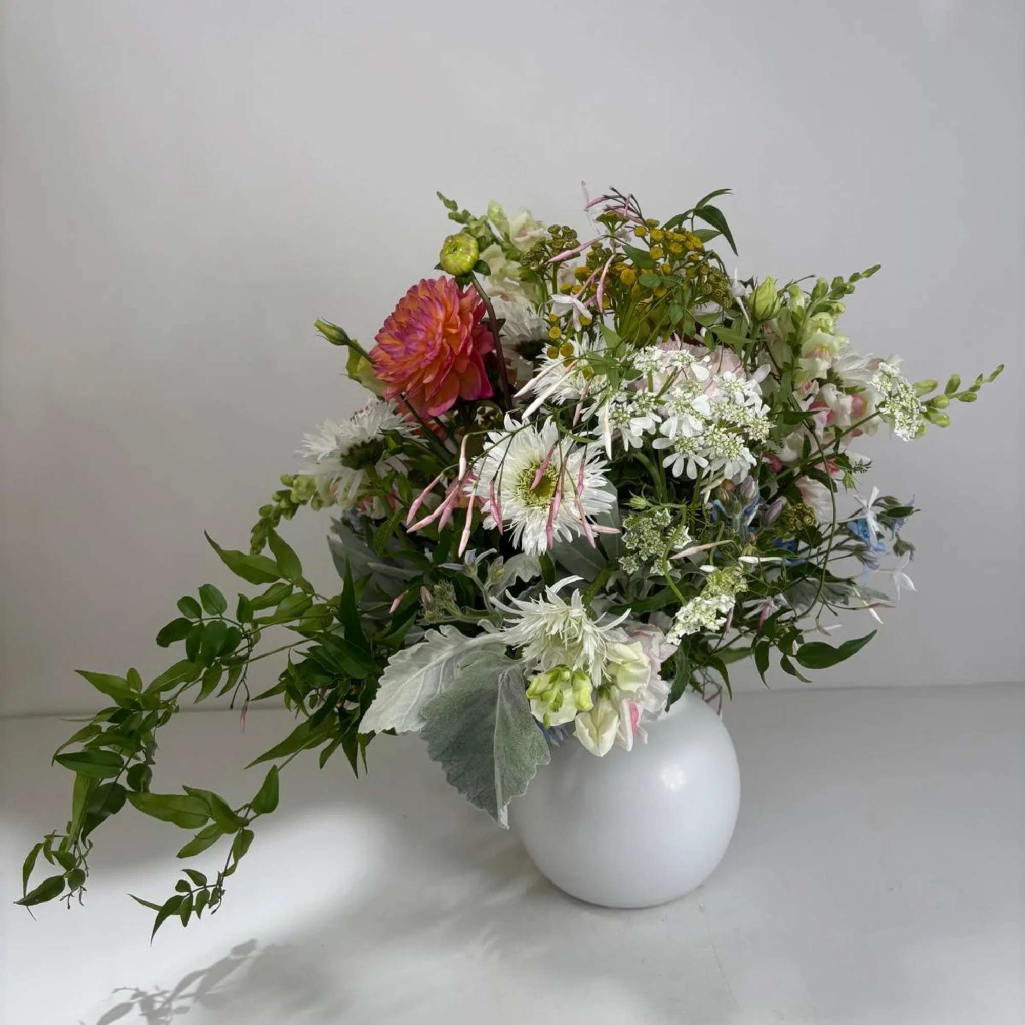Mixed bouquet in a white round vase with white and pink blooms