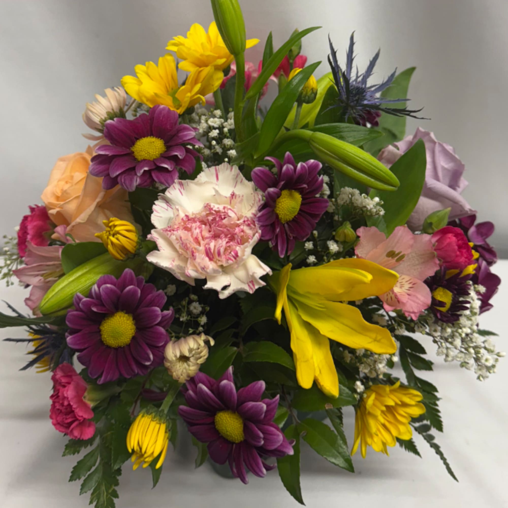 This perky little arrangement includes a variety of roses, daisies, Combined with