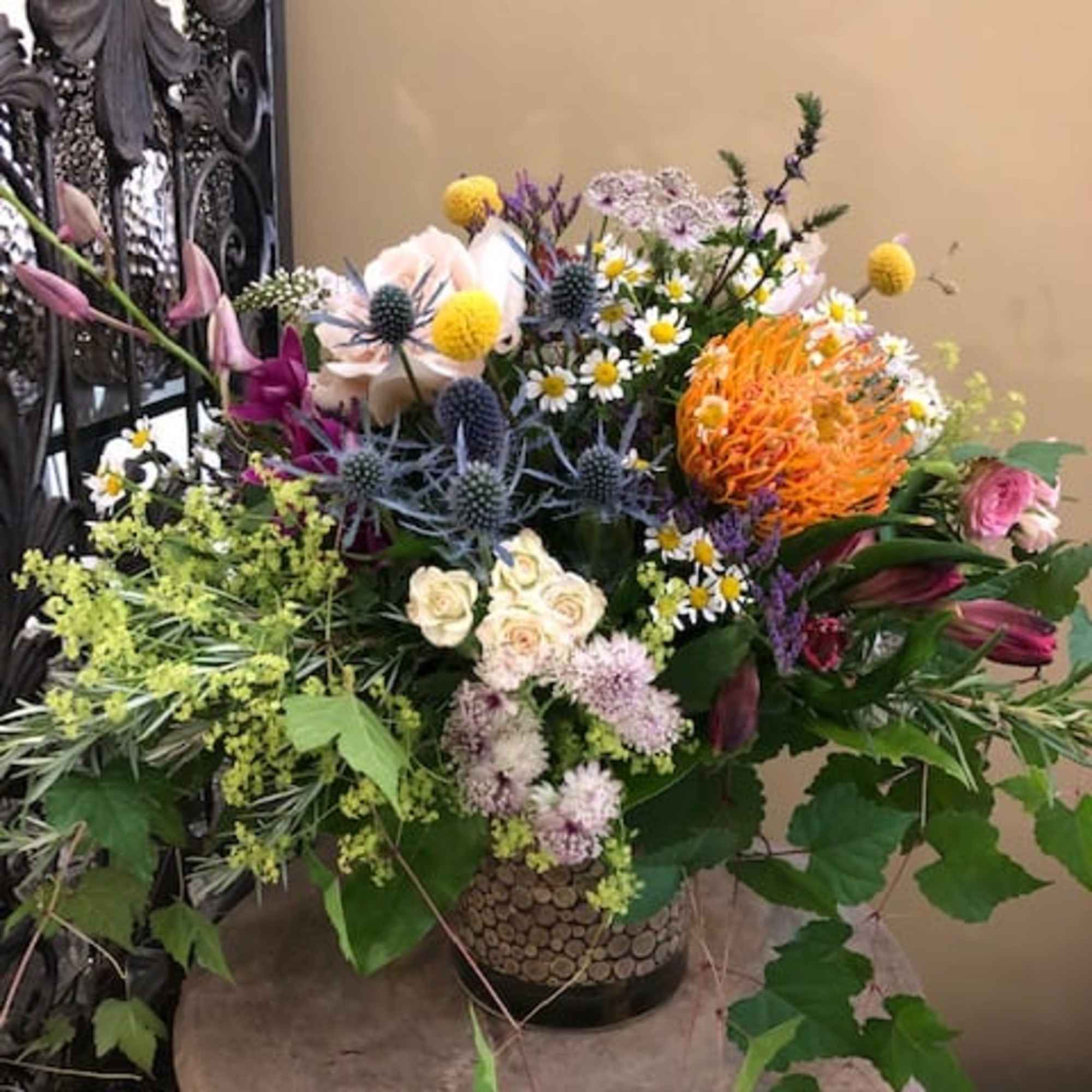 Mixed floral arrangement in a decorative vase with orange, purple, pink, and white blooms