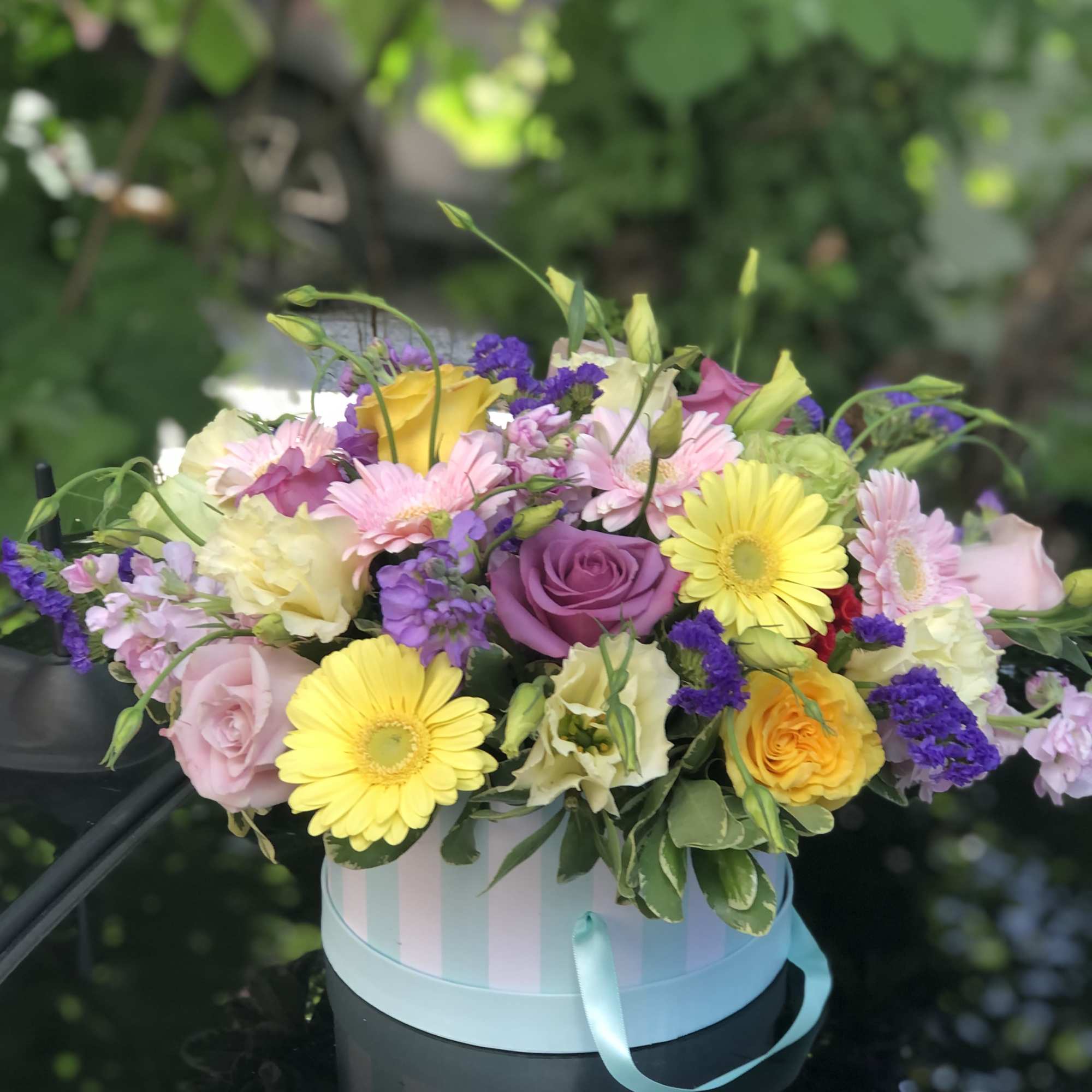 Mixed pastel bouquet in a striped round box with a ribbon