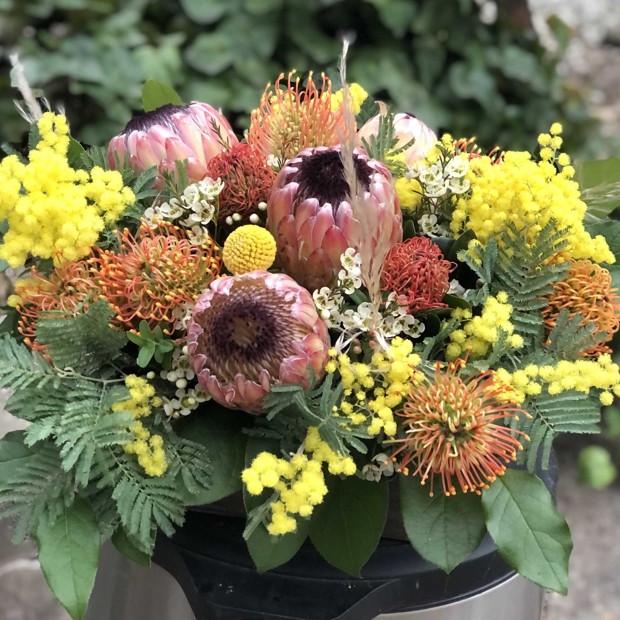 Mixed bouquet with pink protea, orange pincushion blooms, and yellow filler flowers