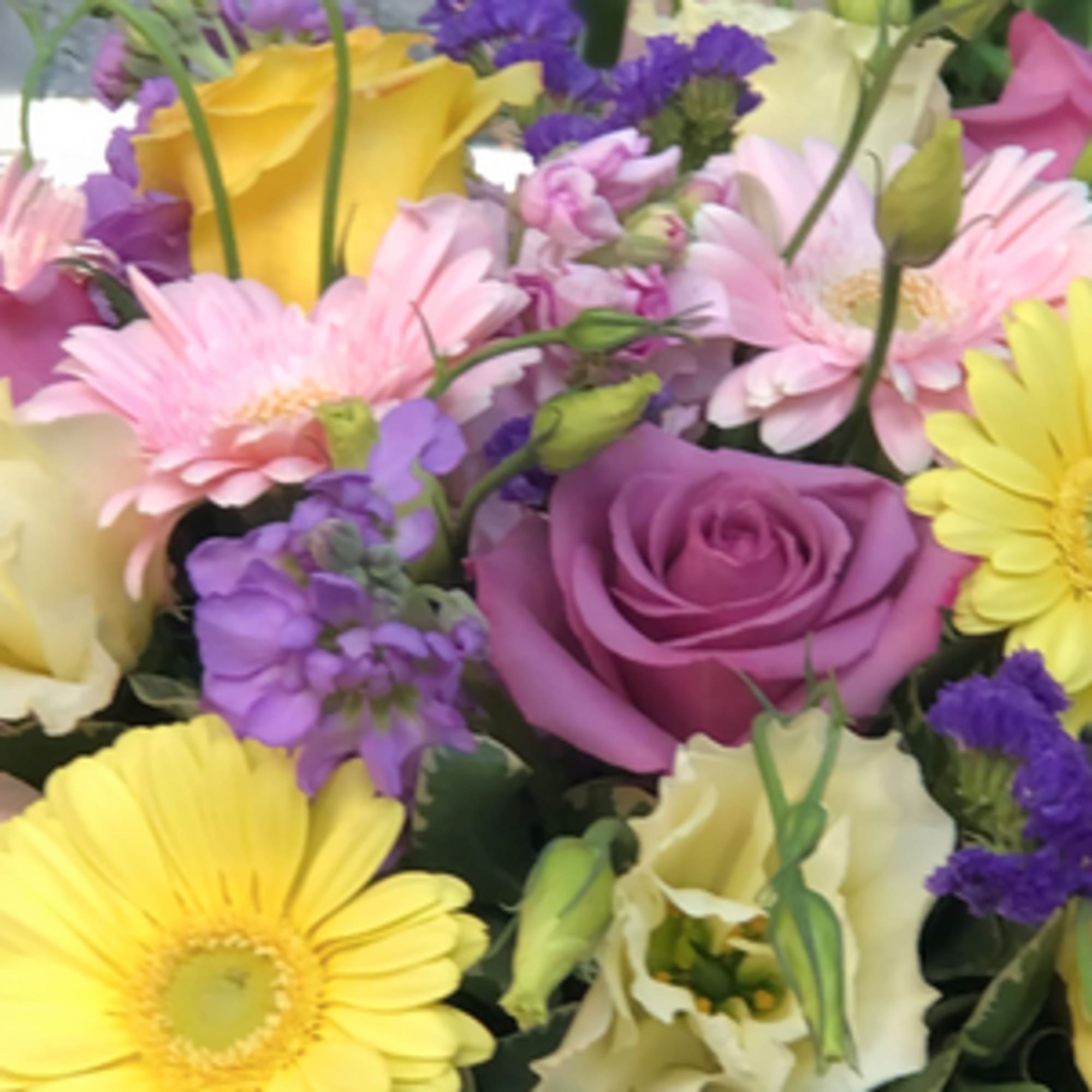 Mixed bouquet with roses, gerbera daisies, and lisianthus in pink, yellow, purple, and white.