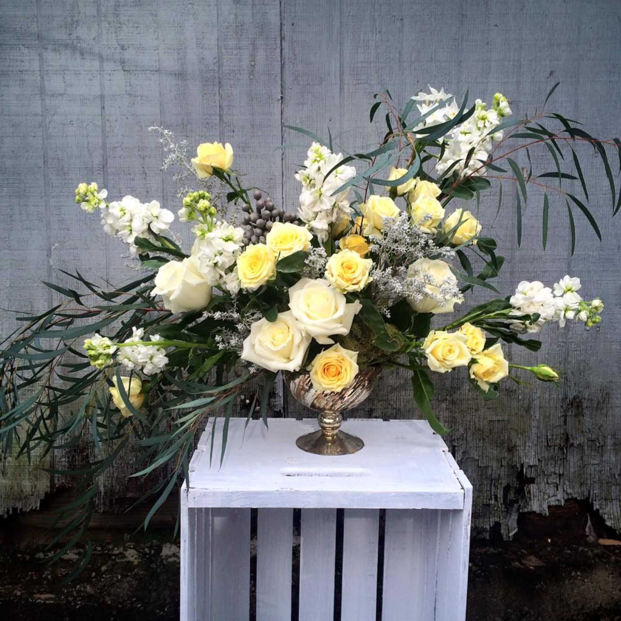 Yellow and white roses arranged in a pedestal vase