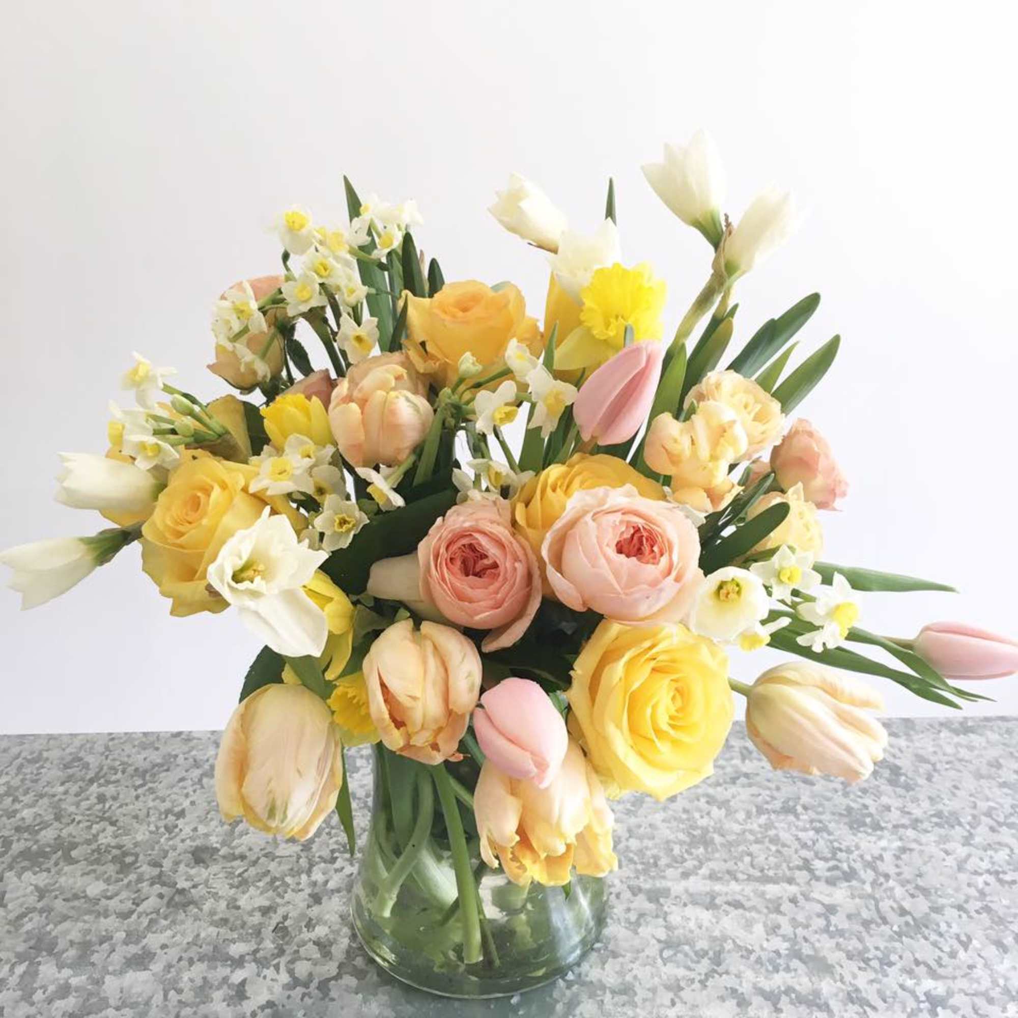 Bouquet of yellow, pink, and white flowers in a clear glass vase