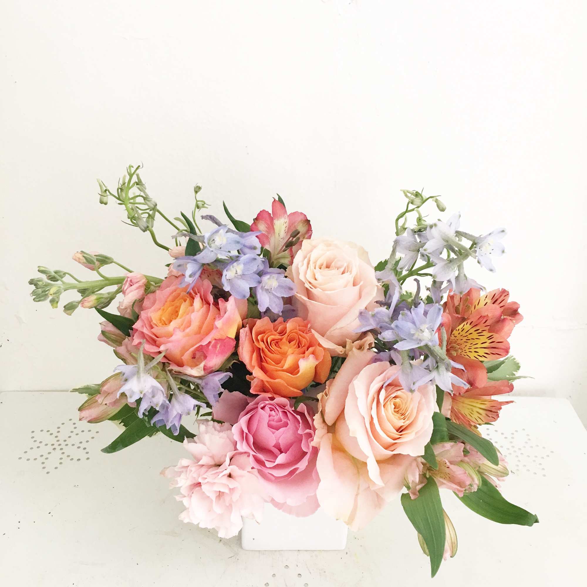 Pastel rose bouquet with blue flowers in a white box