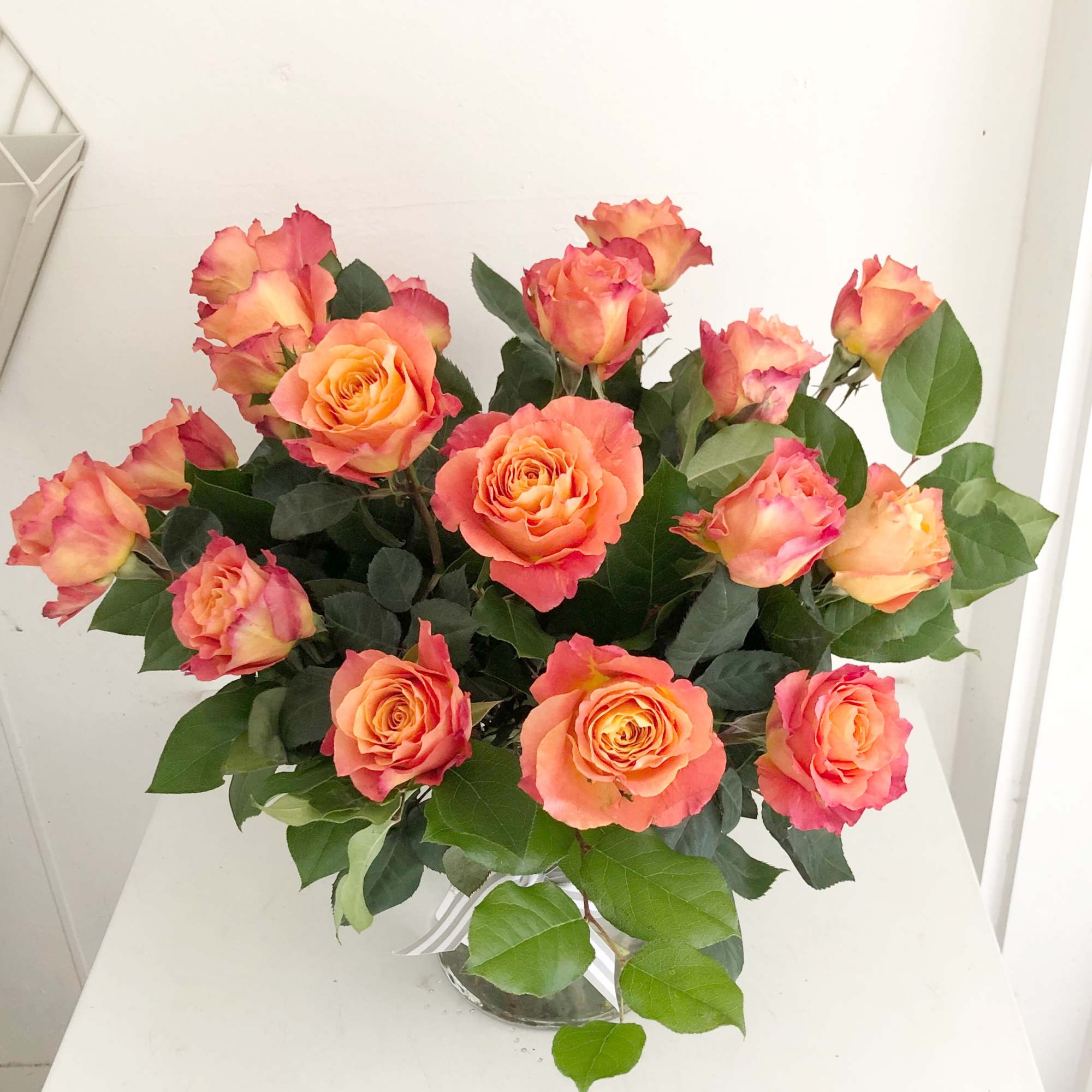 Bouquet of orange-pink roses in a clear glass vase