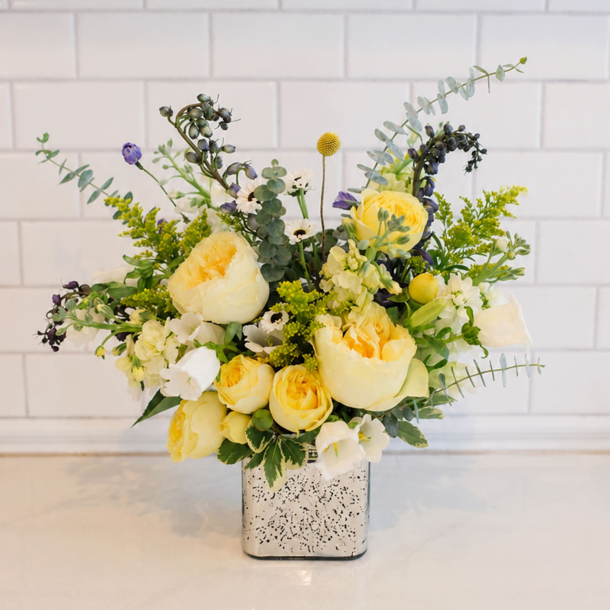 Yellow and white floral arrangement in a square silver vase