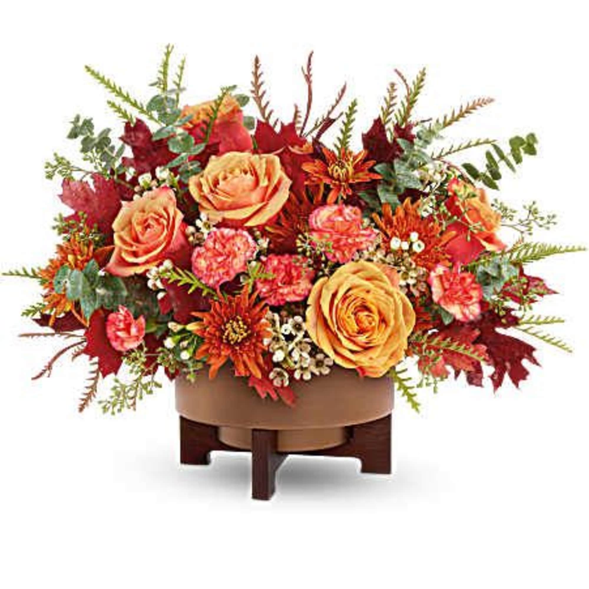 Autumn floral arrangement with orange roses and red blooms in a low container