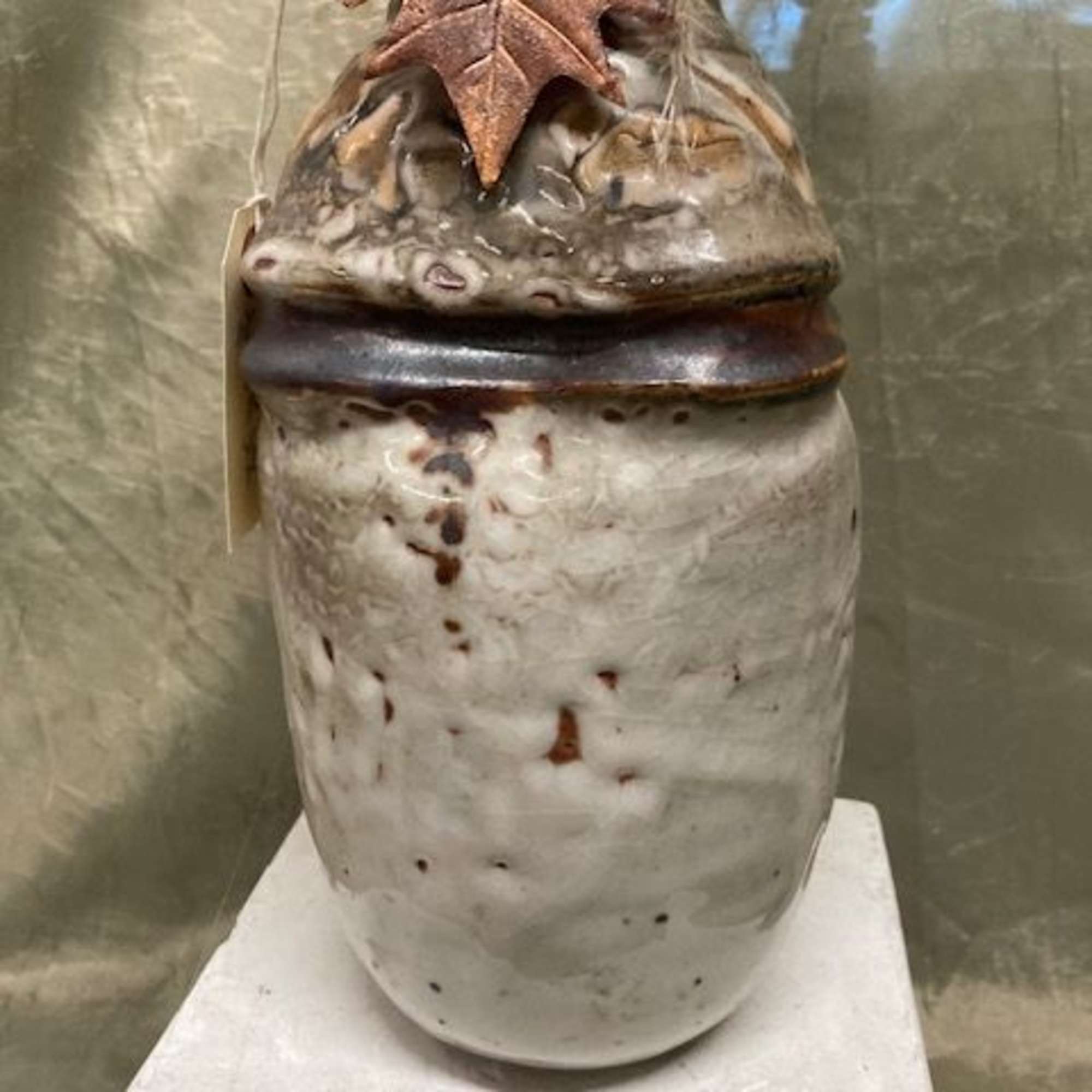 Ceramic jar with a textured leaf decoration on top