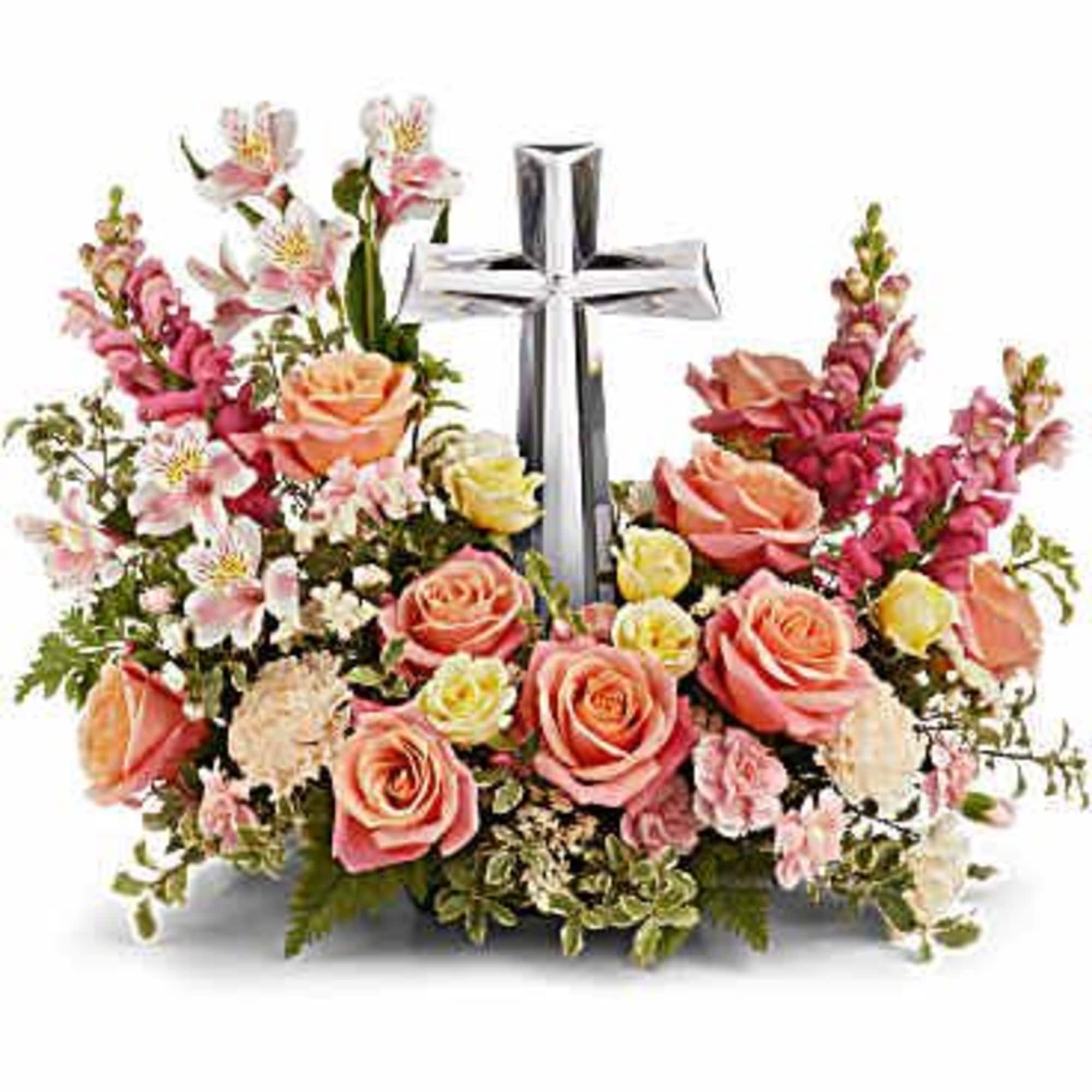 Floral arrangement with a silver cross centerpiece and pink roses