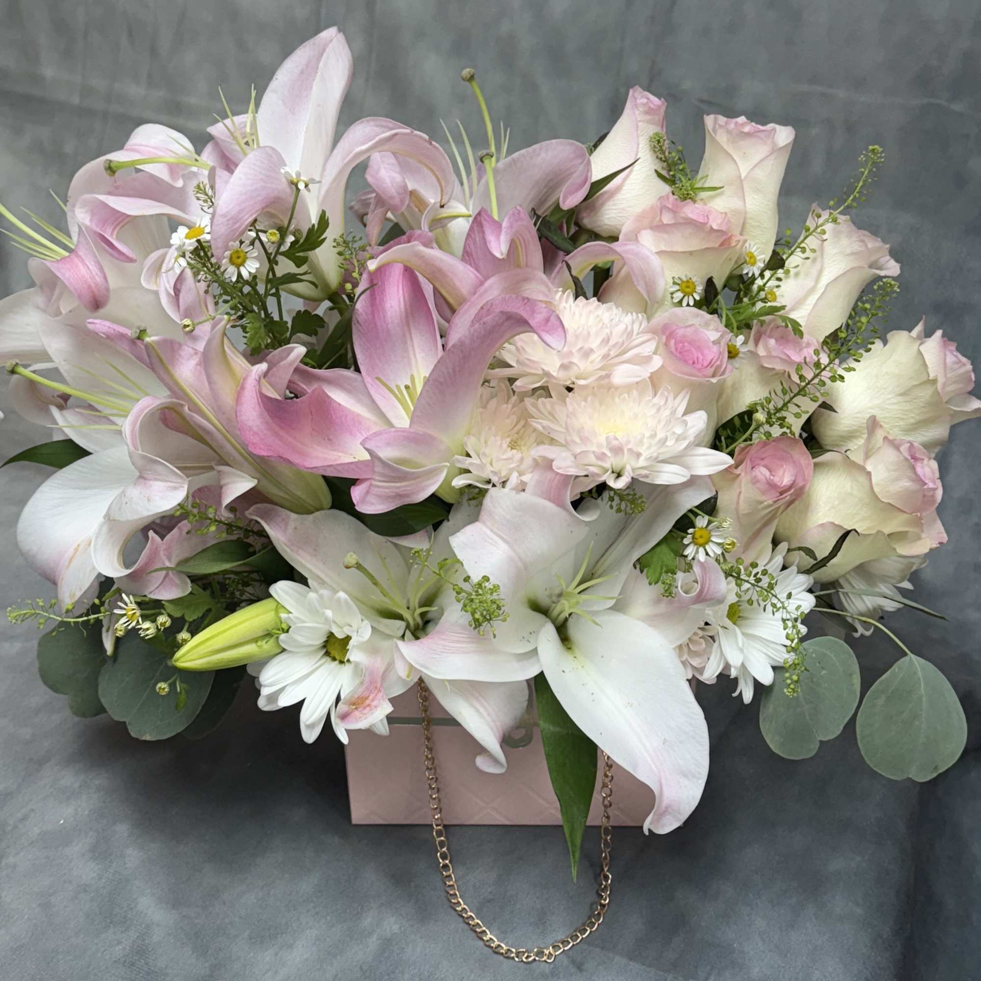 Pink and white lilies with roses and daisies in a gift box