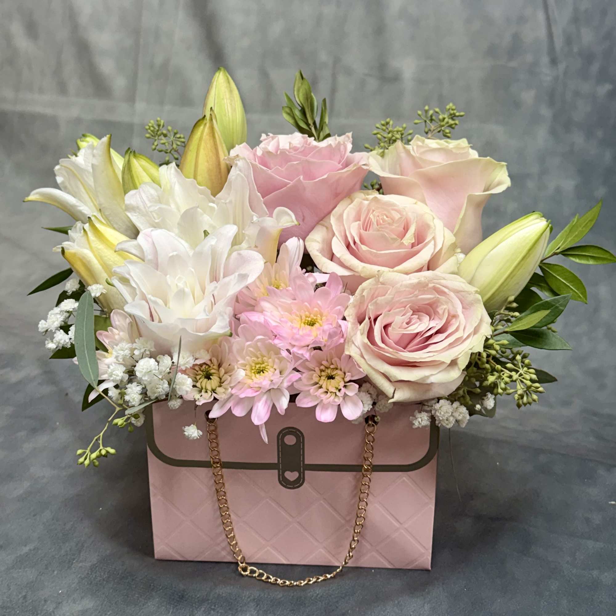 Pink and white flower arrangement in a pink handbag-style box