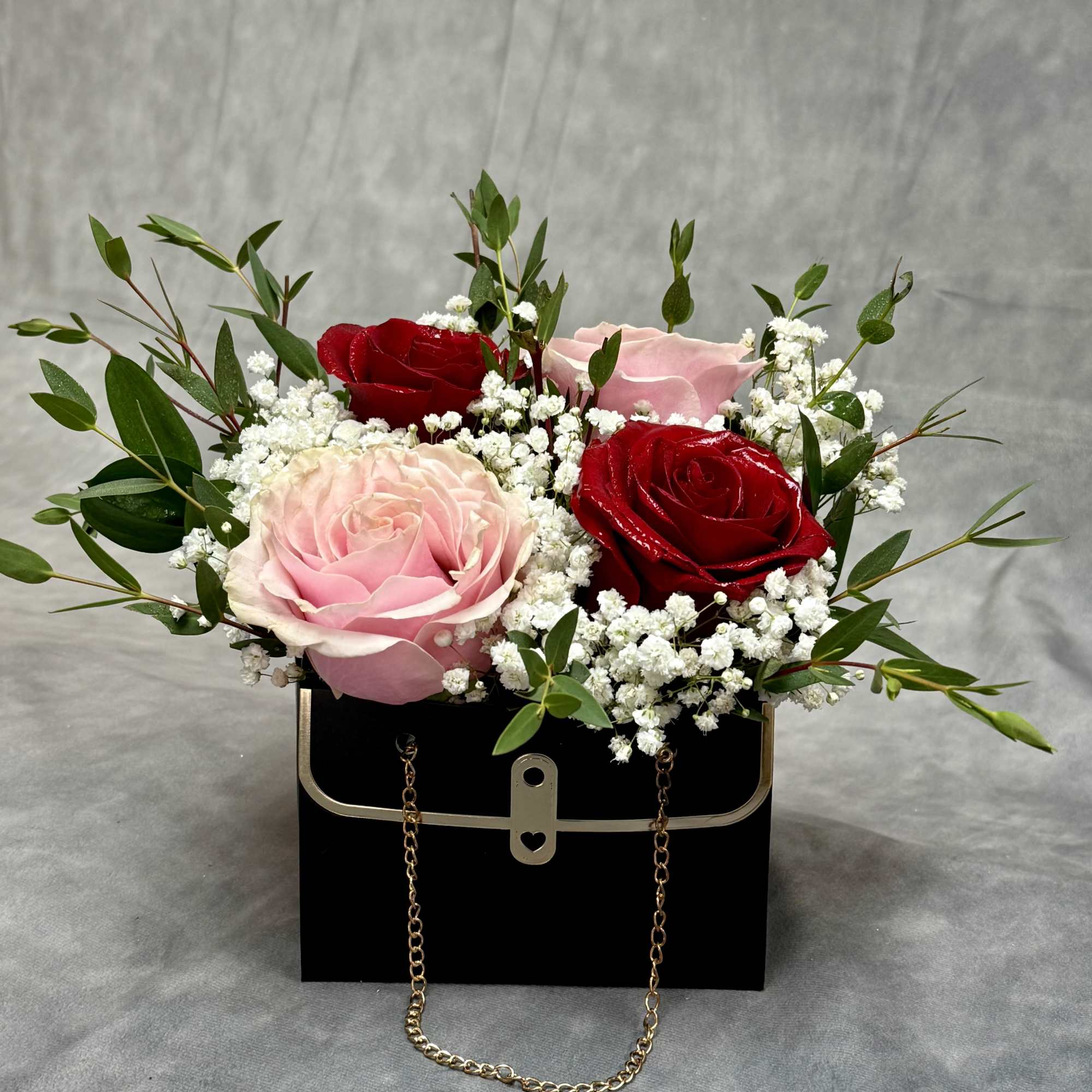 Pink and red roses in a black handbag-style box with white filler flowers