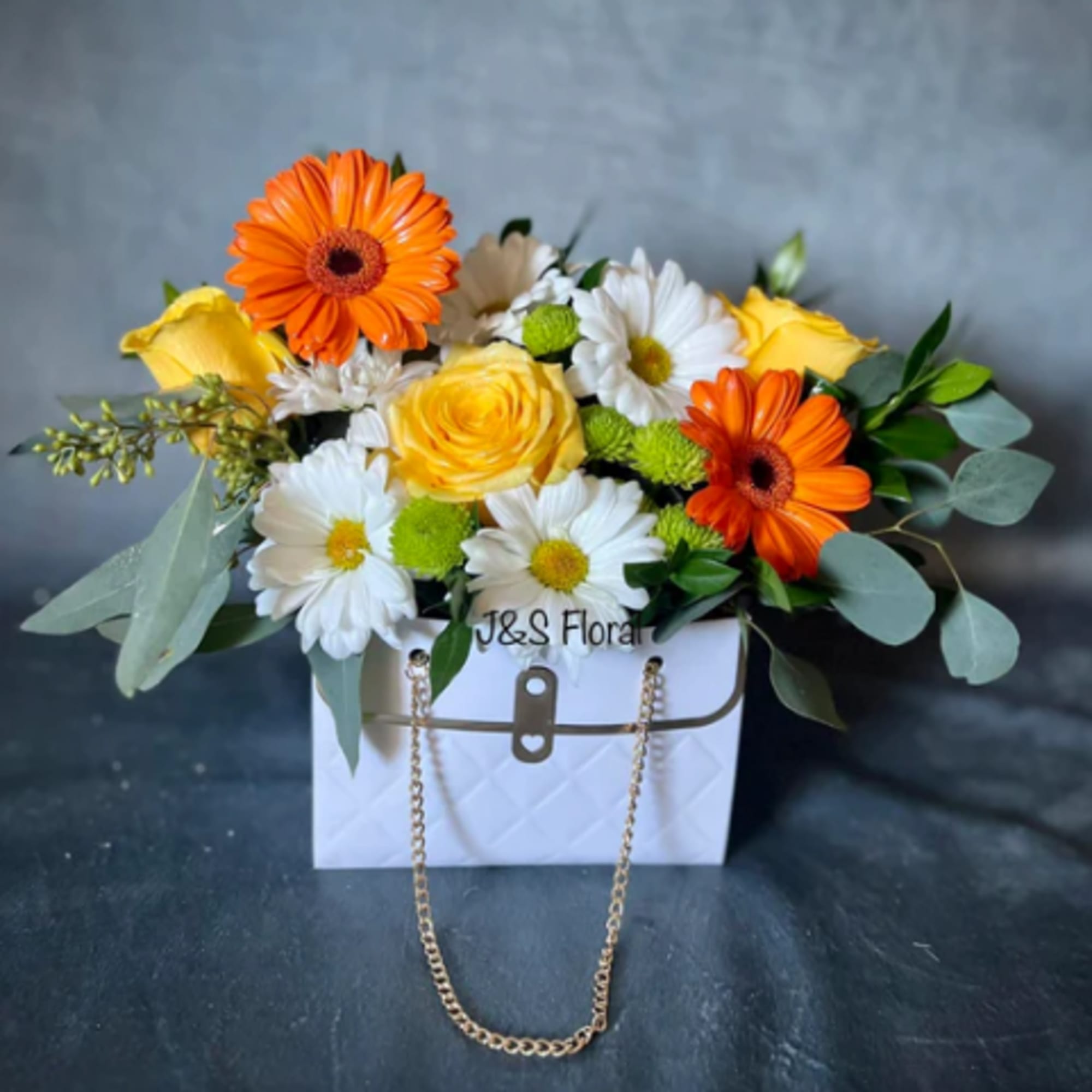 Bouquet of orange and yellow flowers in a white handbag-style box