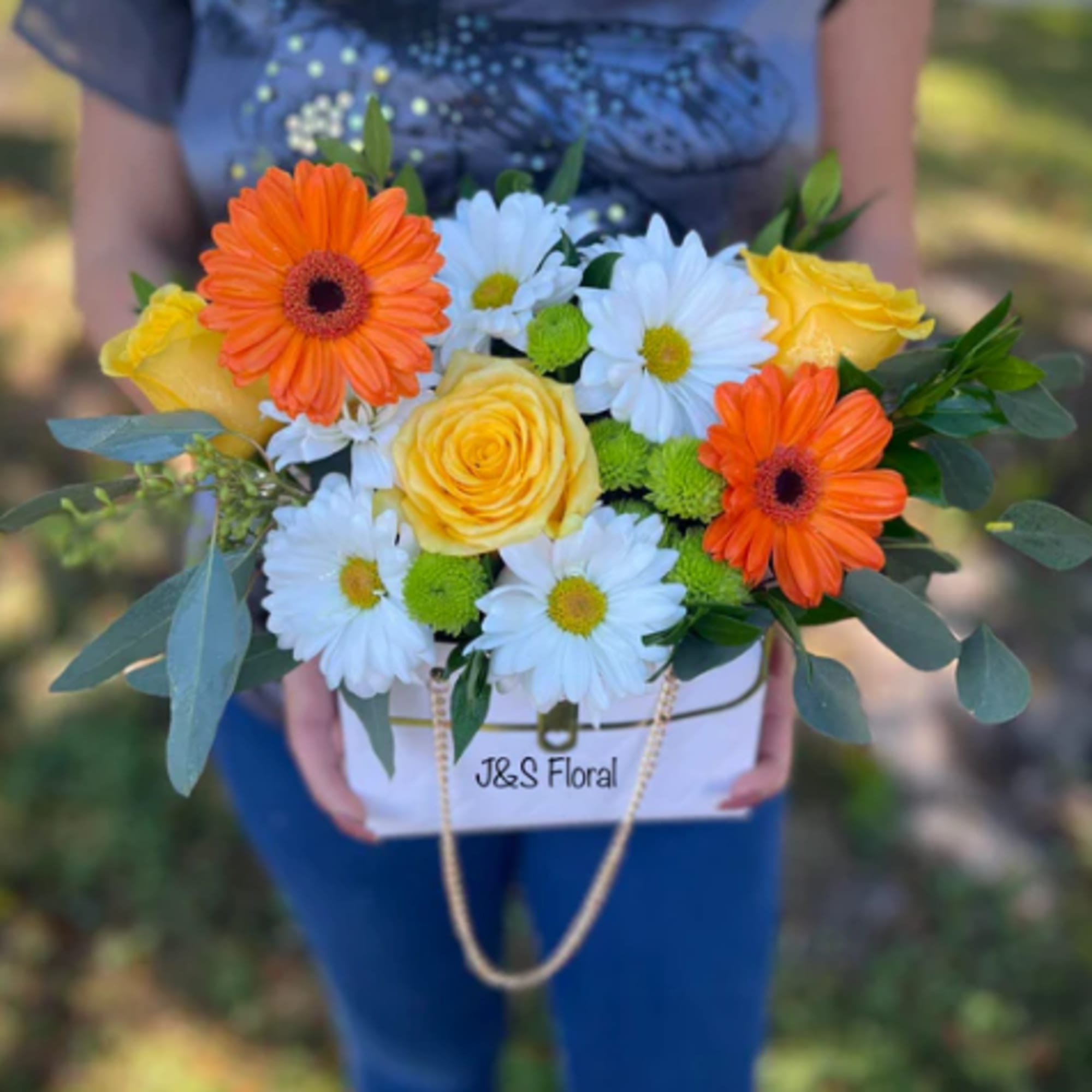 Bouquet of orange gerbera daisies, yellow roses, and white daisies in a white box