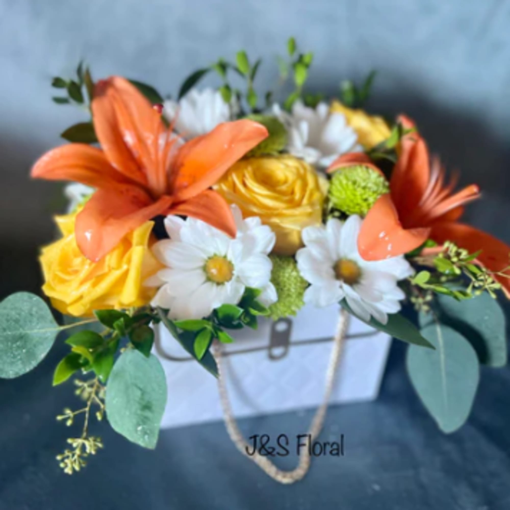 Orange lilies and yellow roses in a white box with daisies