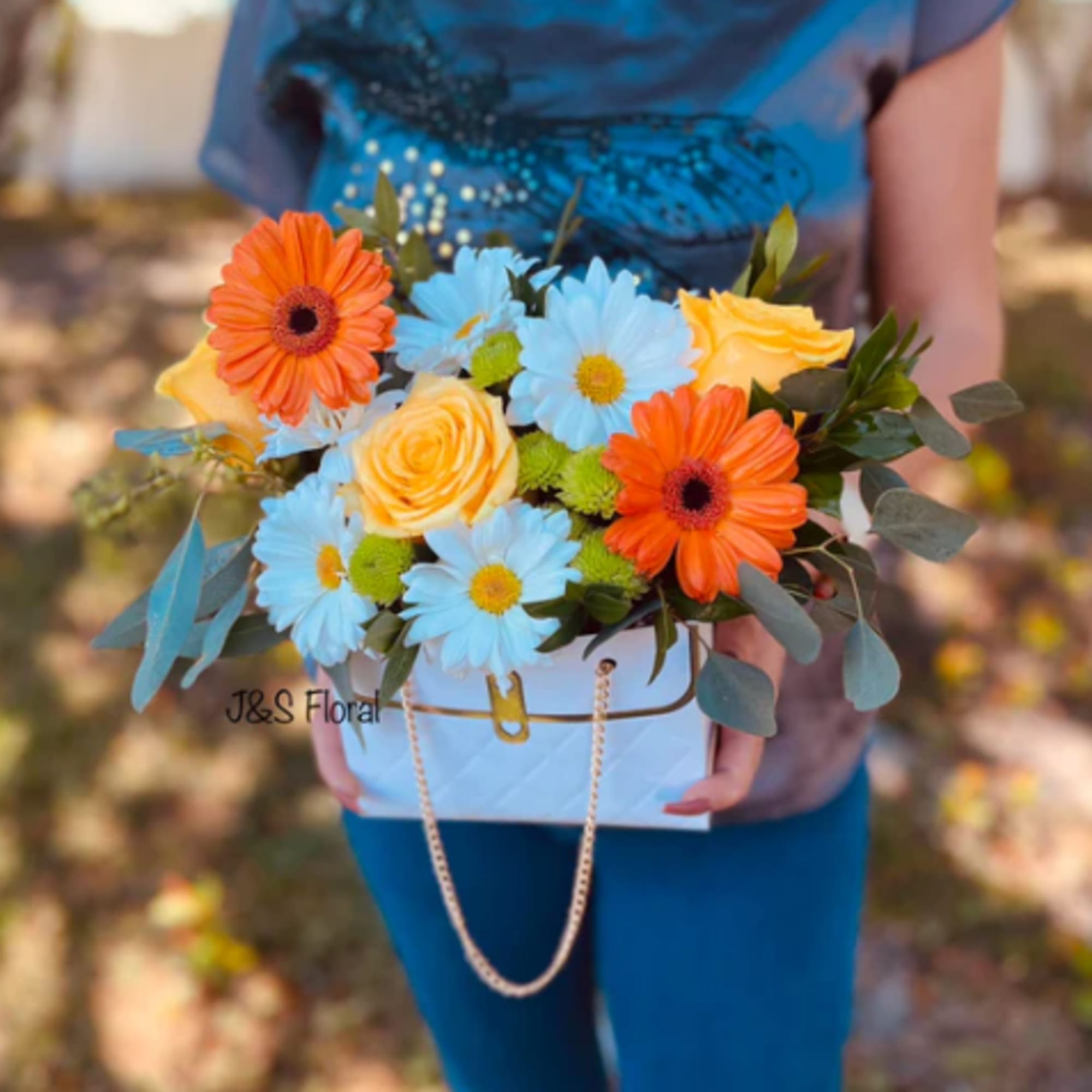 Bouquet of blue daisies, orange gerbera daisies, and yellow roses in a white box