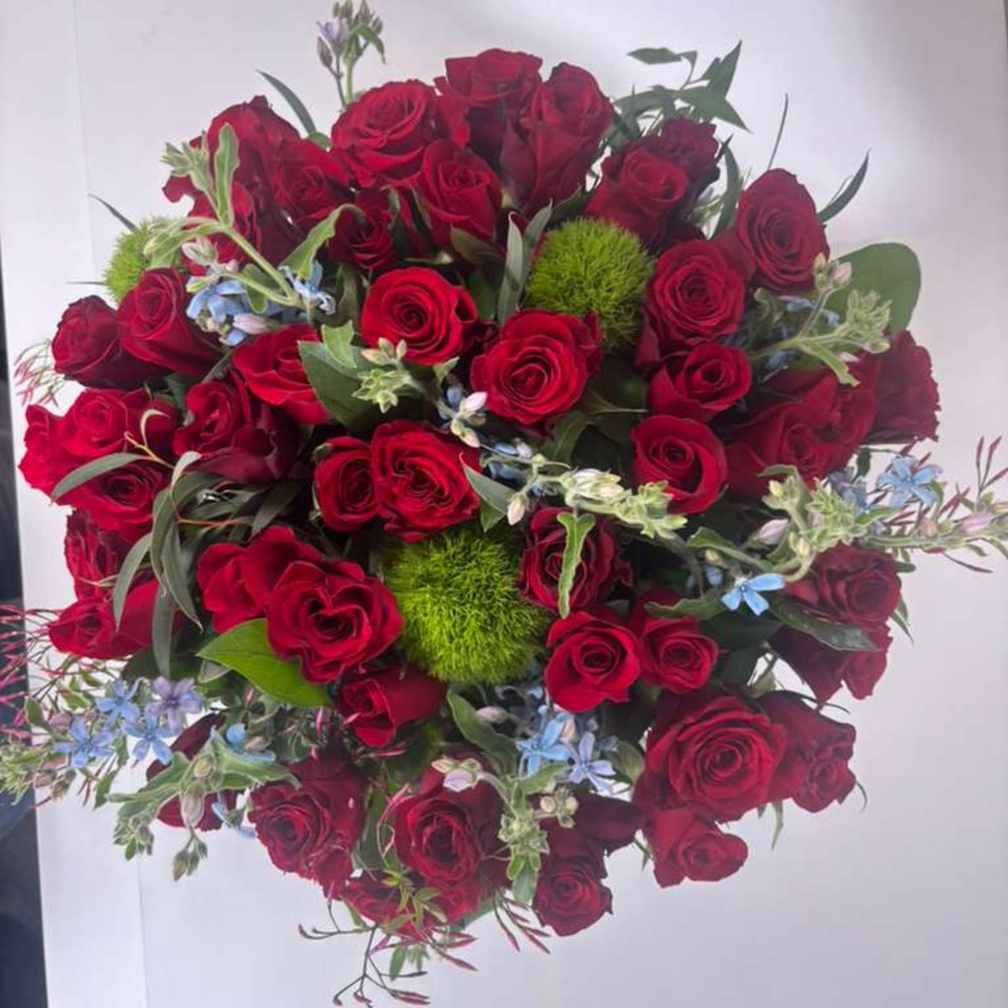 Bouquet of red roses with small blue flowers and green accents