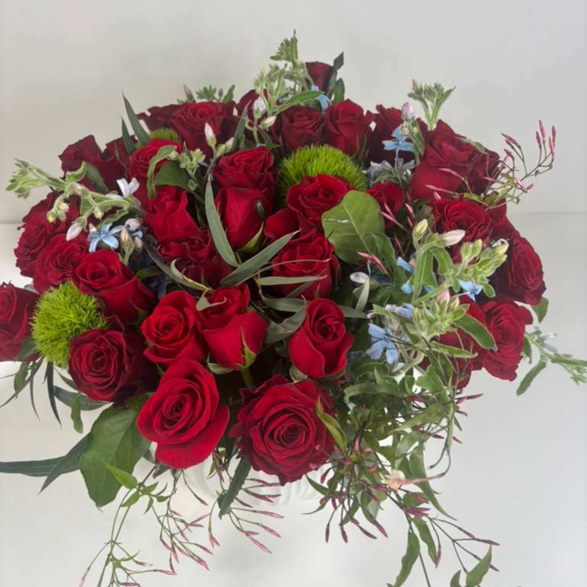 Bouquet of red roses with green accents and trailing foliage