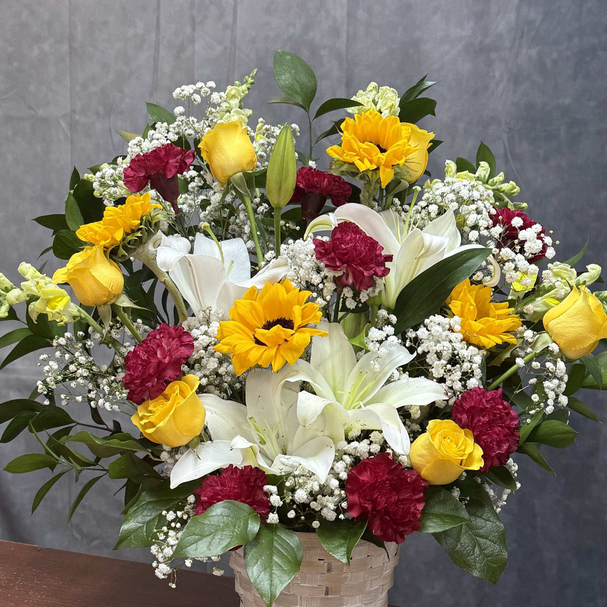 A cheerful blend of golden sunflowers, yellow roses, red carnations, and a