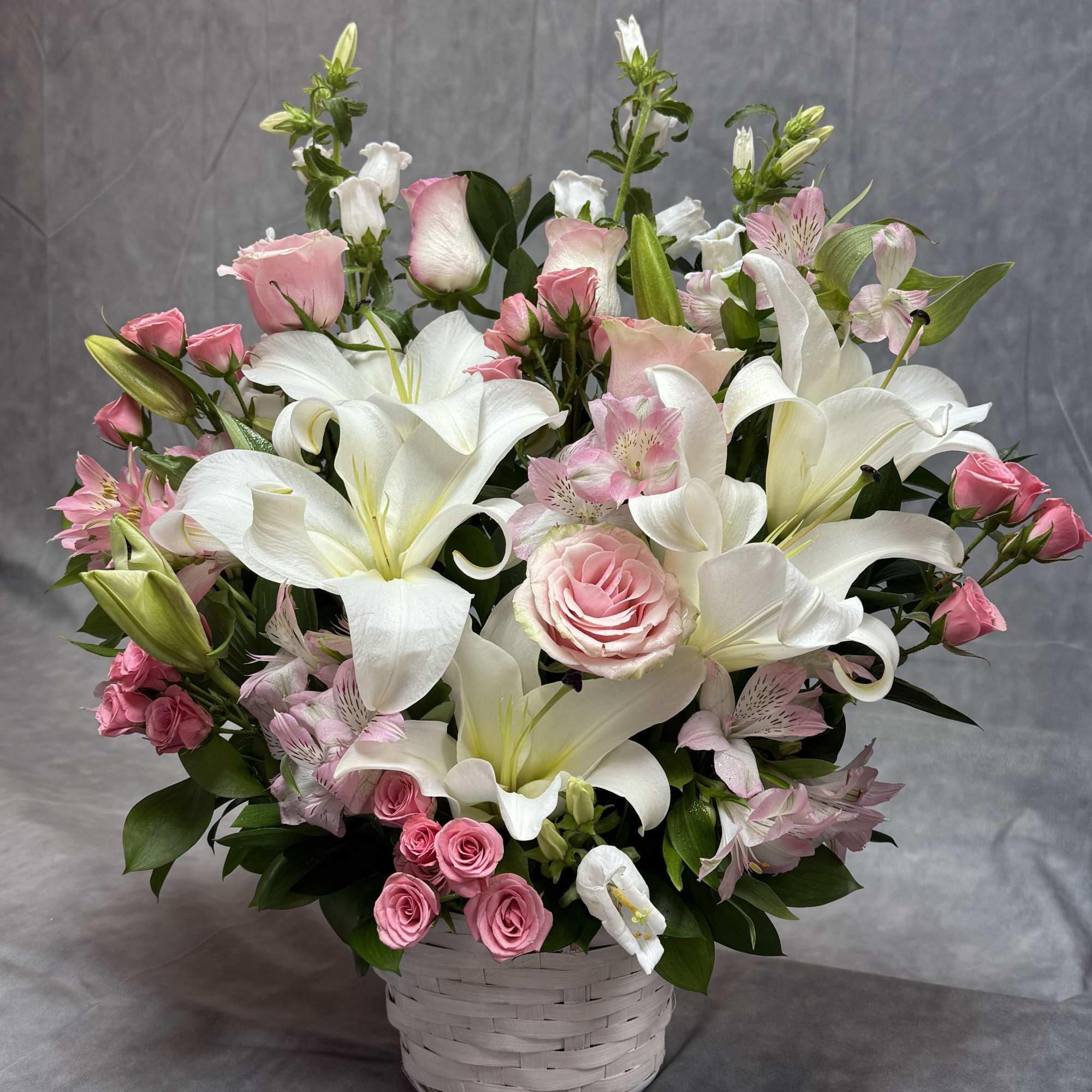 Pink roses and white lilies arranged in a white basket, photo 2 of 2