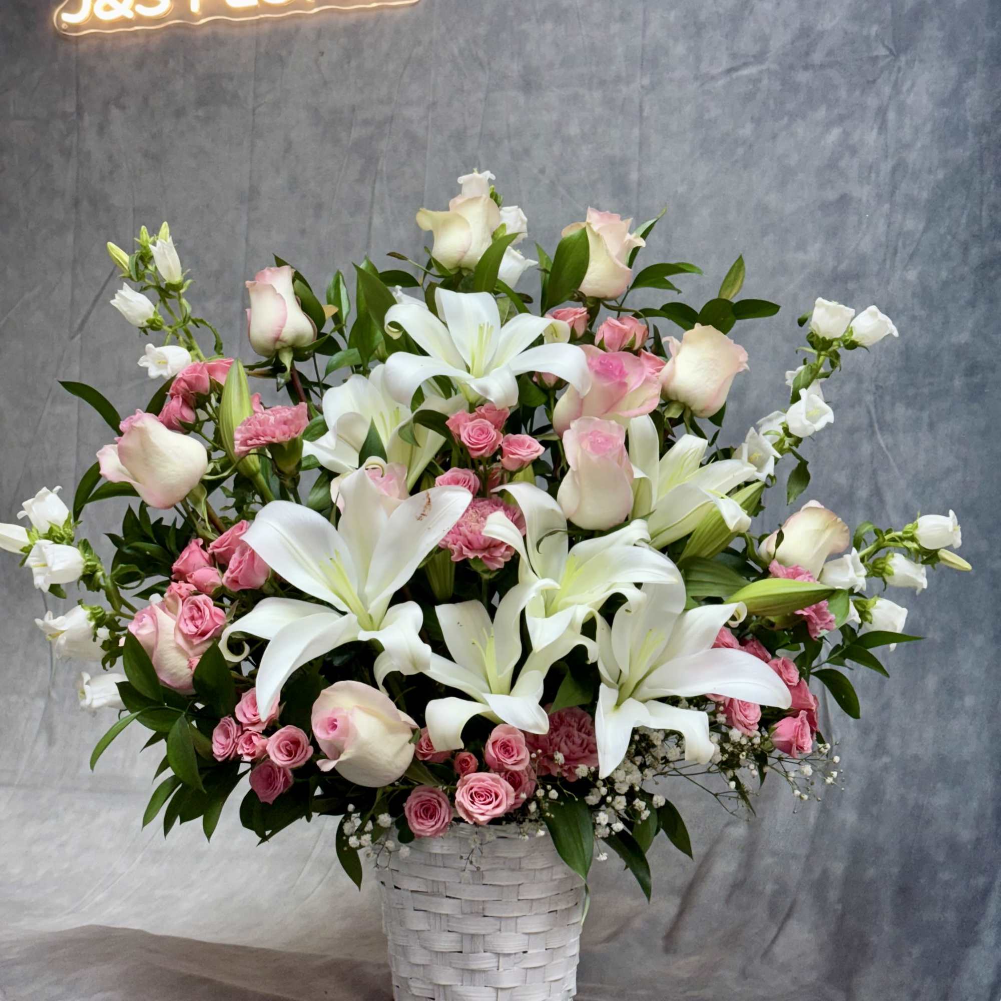 Pink roses and white lilies in a white woven basket