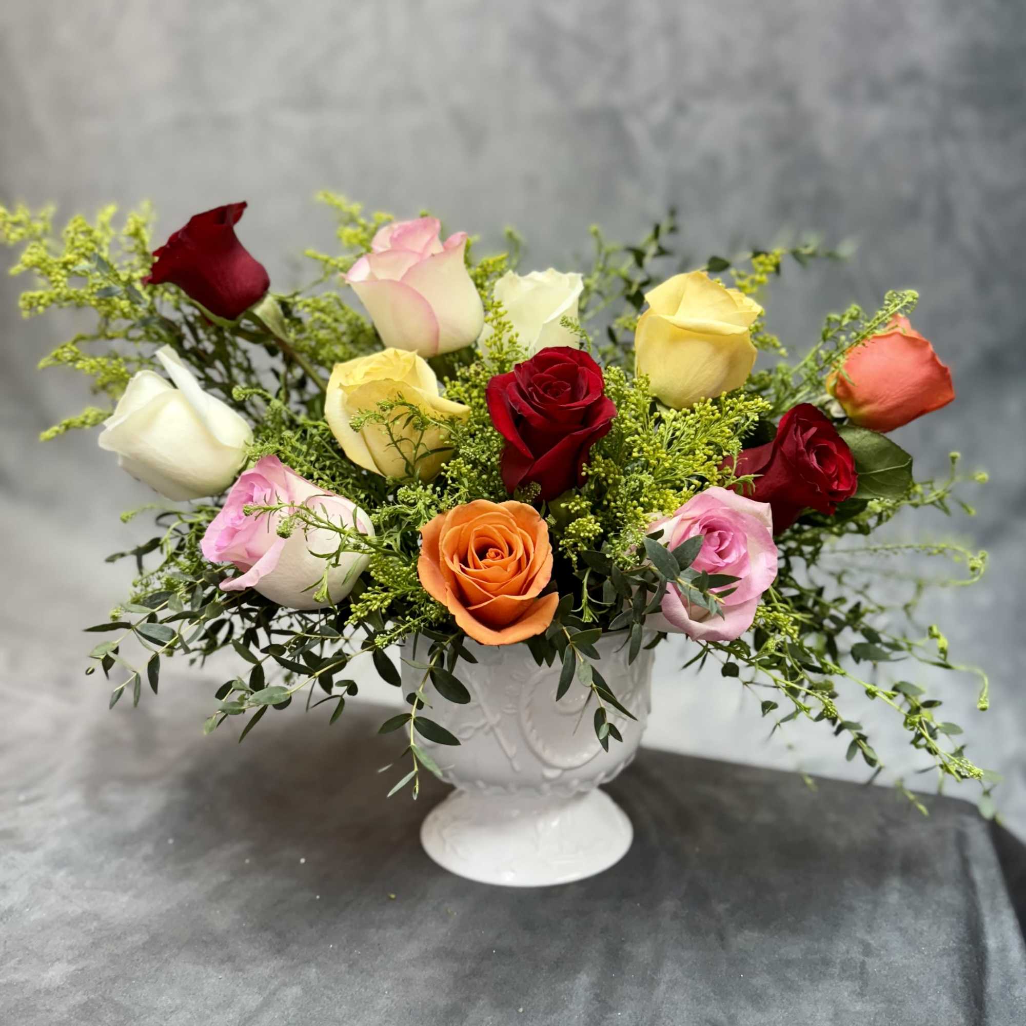 Mixed roses arranged in a white pedestal vase