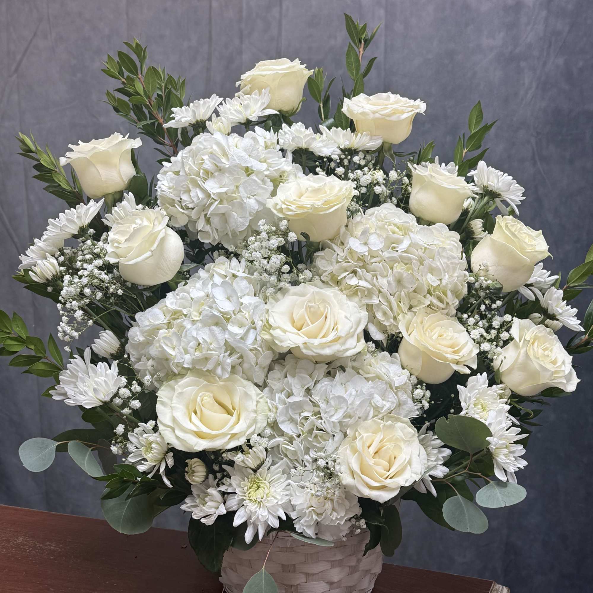  An elegant all-white display featuring lush hydrangeas, timeless roses, and soft