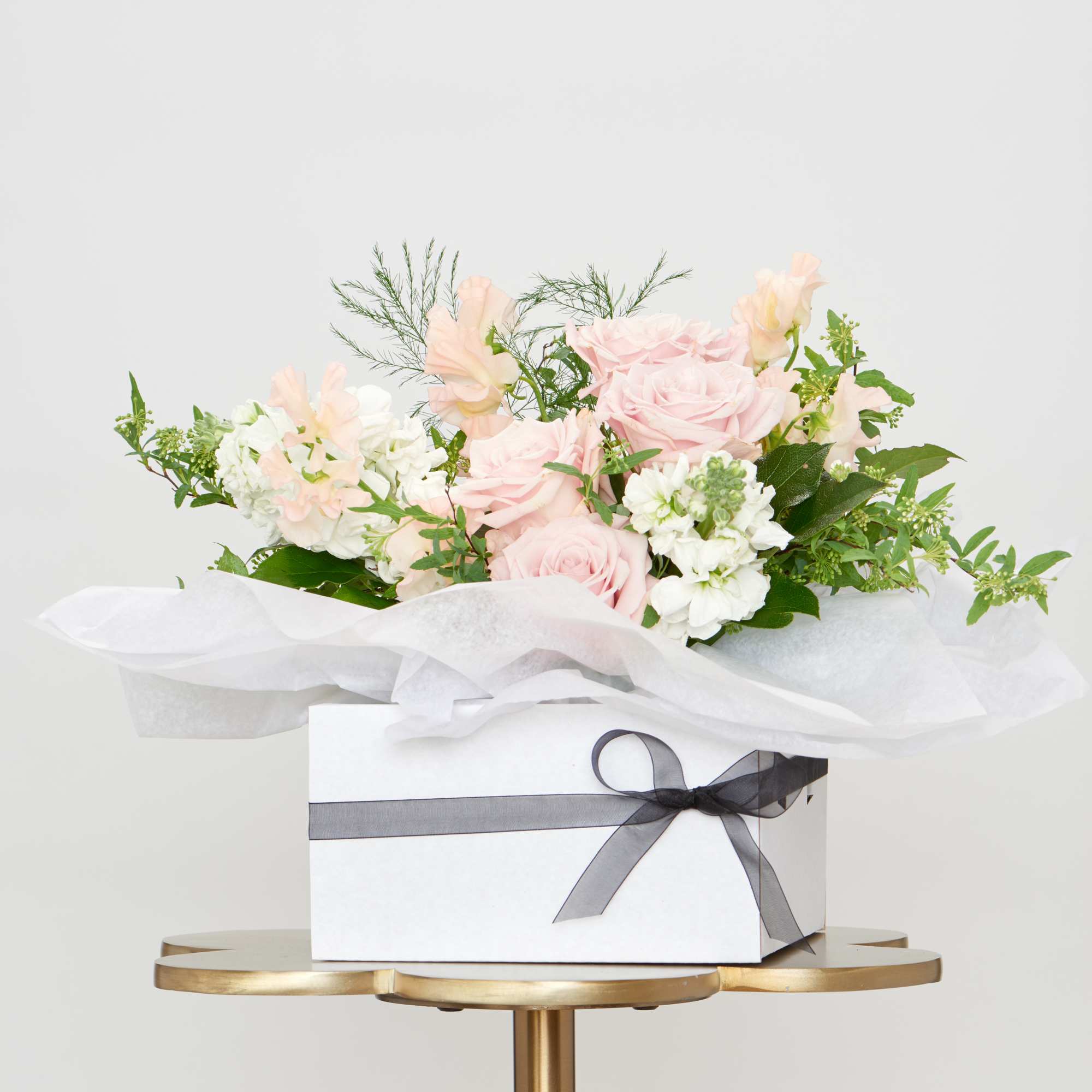 Pink and white floral arrangement in a white gift box with a gray ribbon