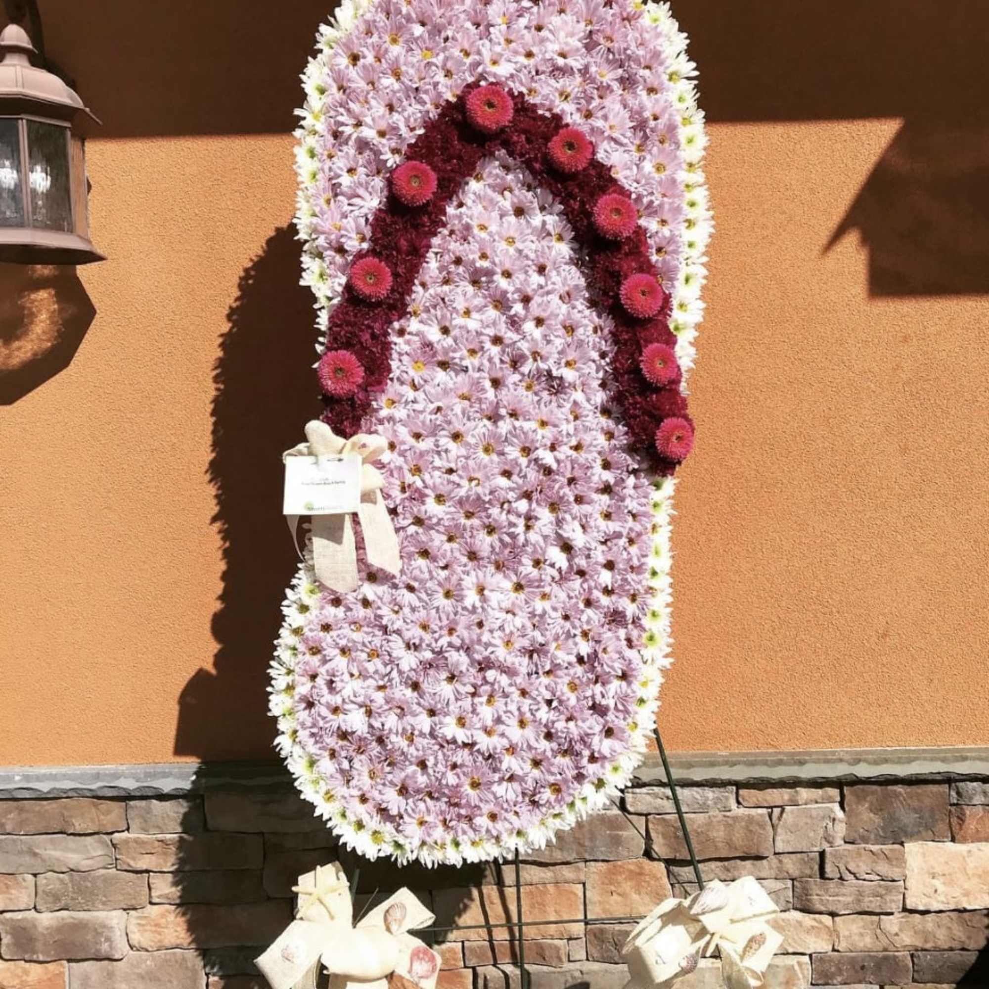 Tall standing floral tribute of pink and white flowers with a dark pink arch