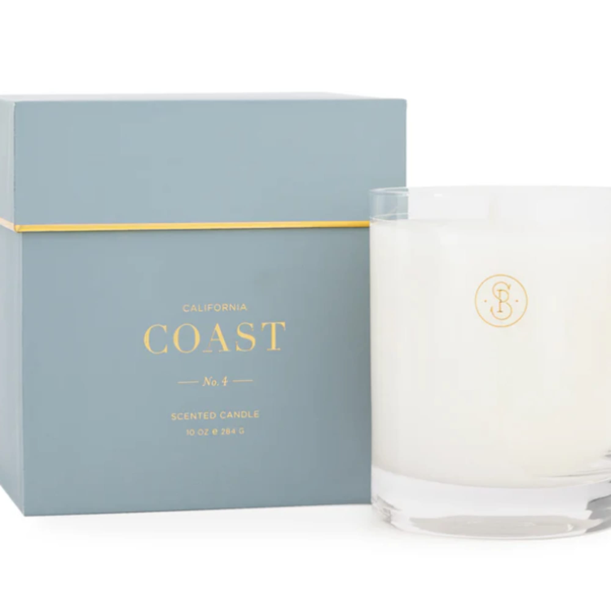 White scented candle in a glass tumbler beside a blue gift box