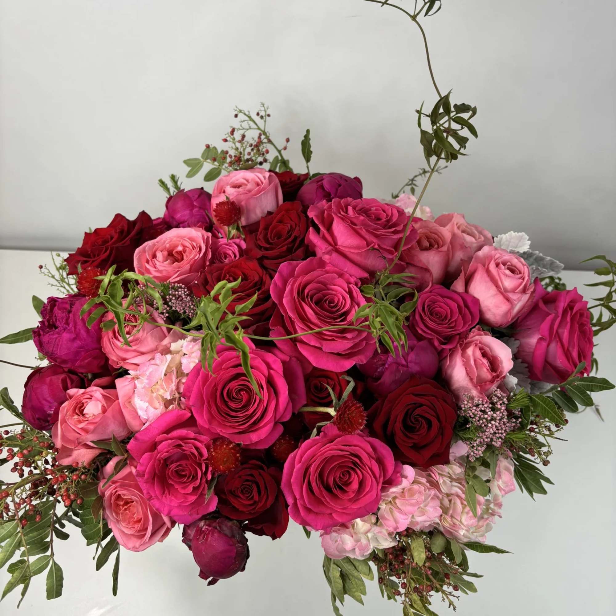Bouquet of pink and red roses with greenery on a white background