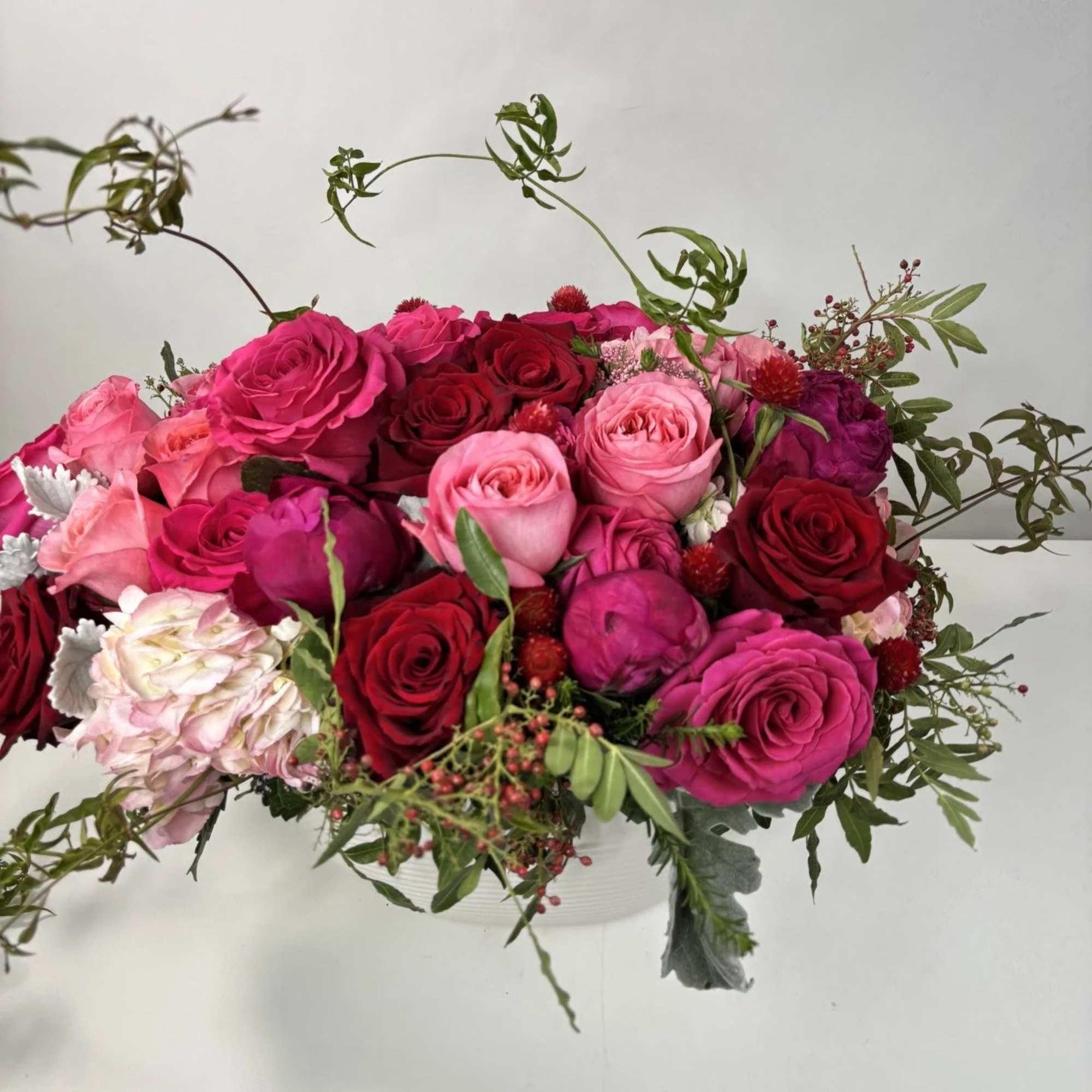 Mixed pink and red rose arrangement in a white container