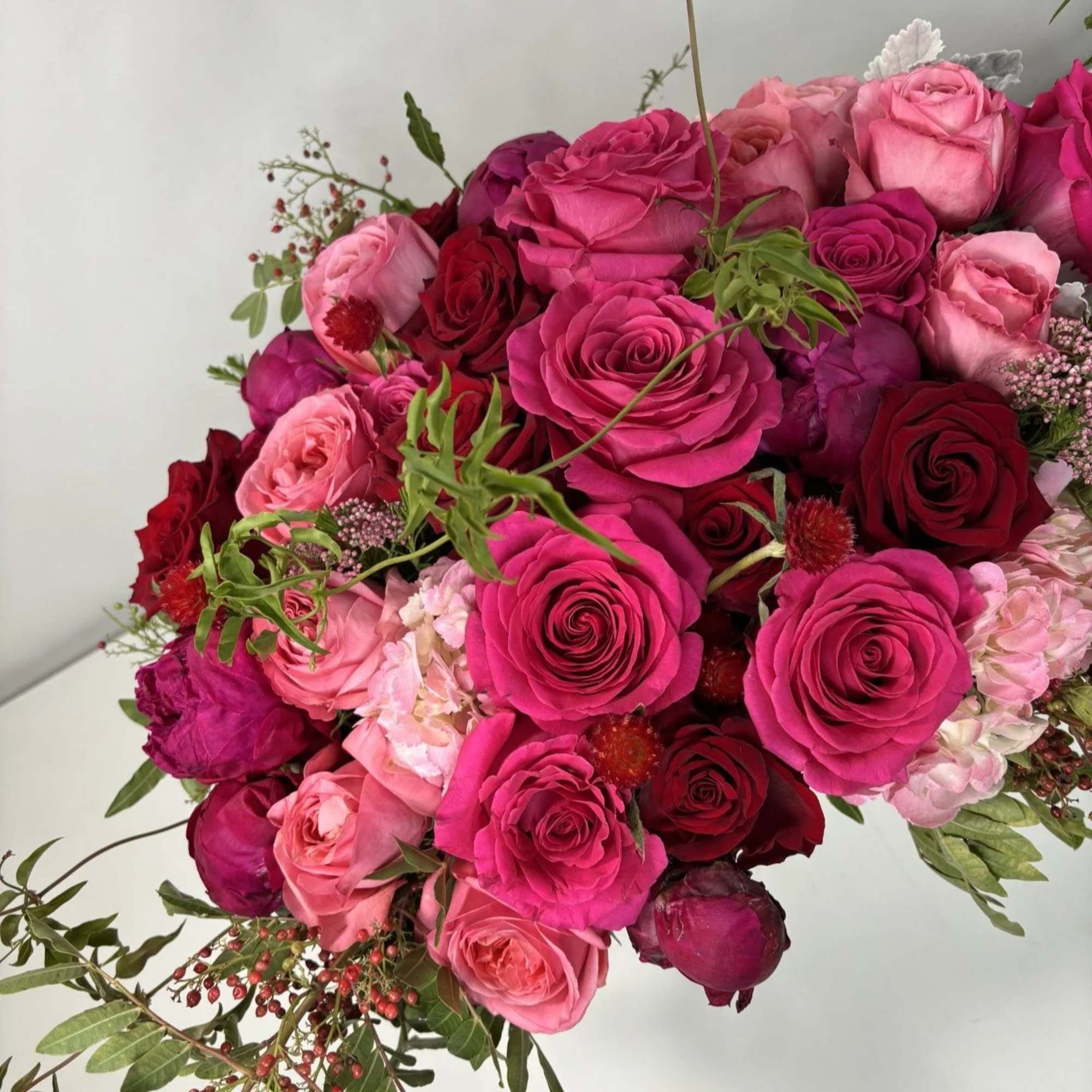 Bouquet of pink and red roses with small berry accents